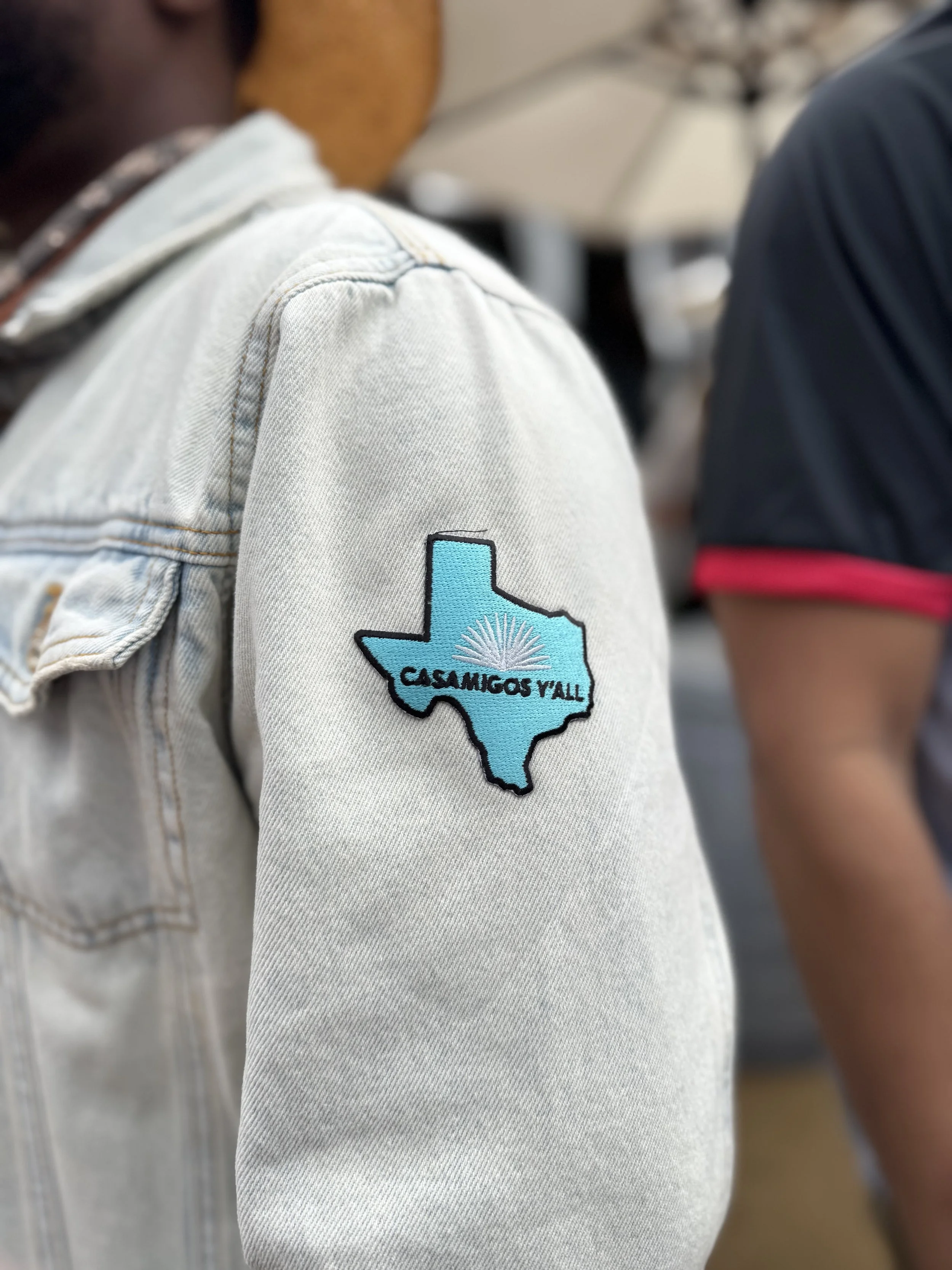 Texas shaped blue patch with casamigos logo heat pressed live on a denim jacket.