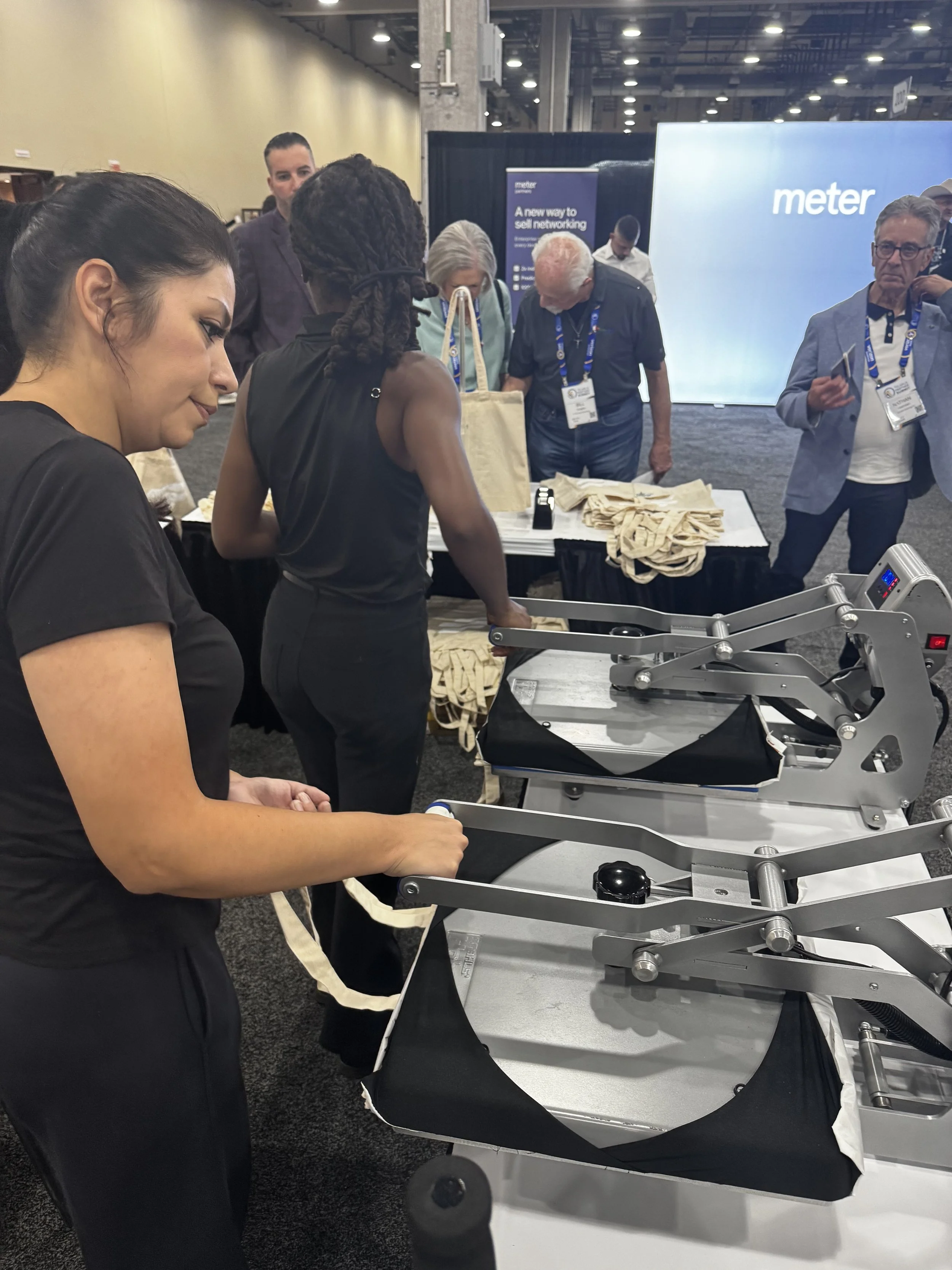 Apdat staff engaging with guests and heat pressing totes live on site