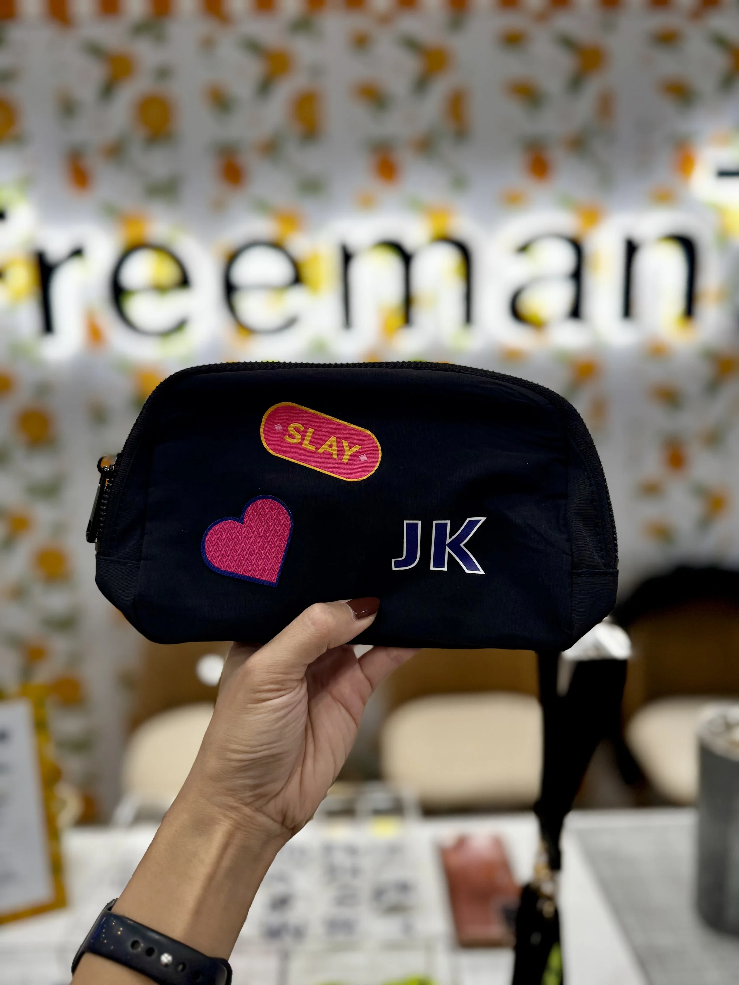 Black belt bag with woven patches and monogrammed decals heat pressed live on site at expo expo 2025