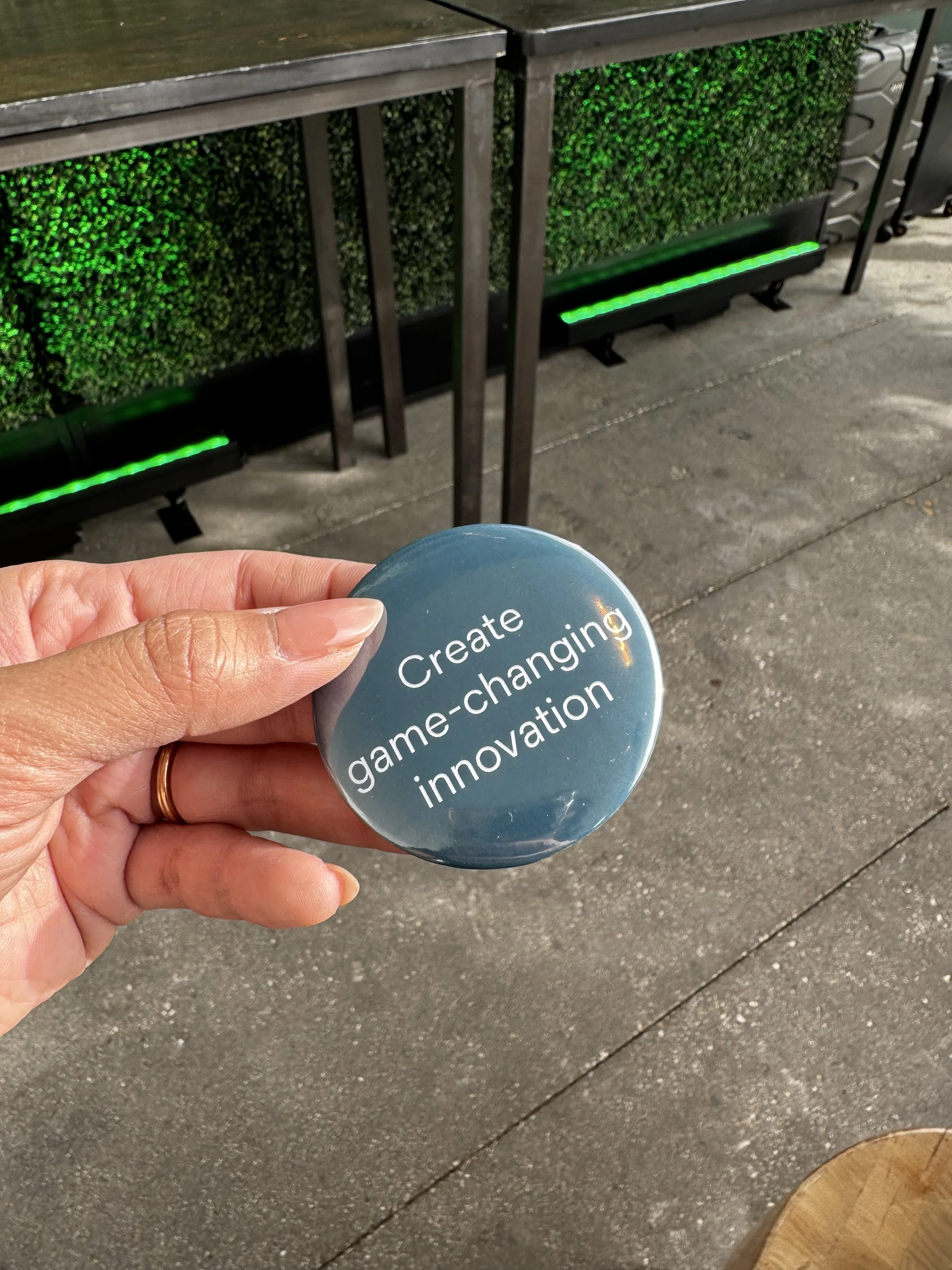 Button that reads 'create game changing innovation' one of the many whys presented by guests of solventum, which were printed live on site then pressed into a button using our presses.