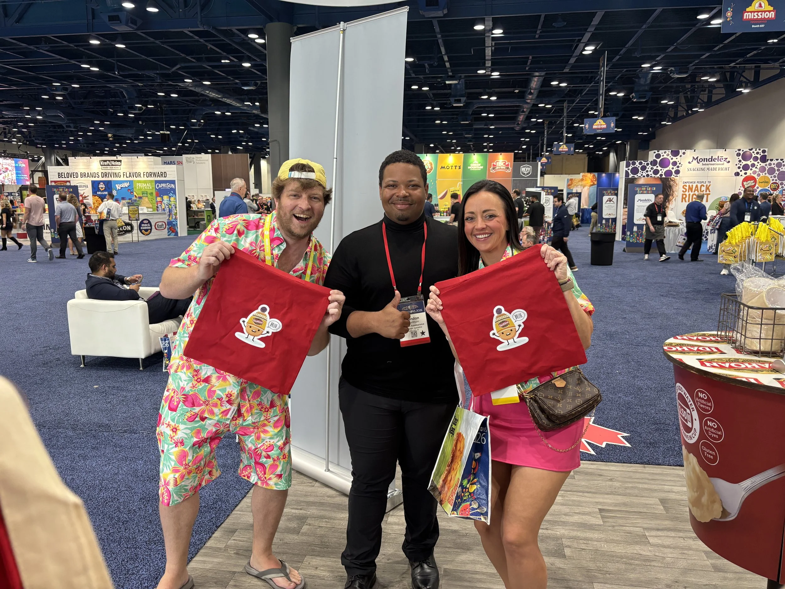 two very excited attendees pose with apdat staff and their hot off the presses totes