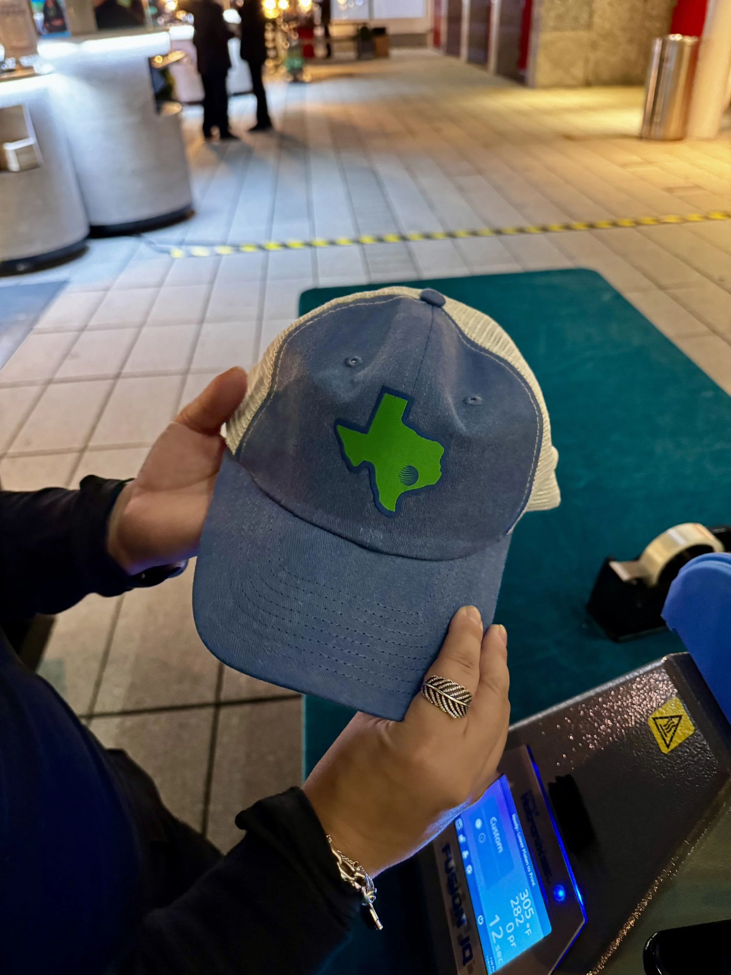 close up of what a finished hat looks like after having custom woven patch applied via heat press live on site