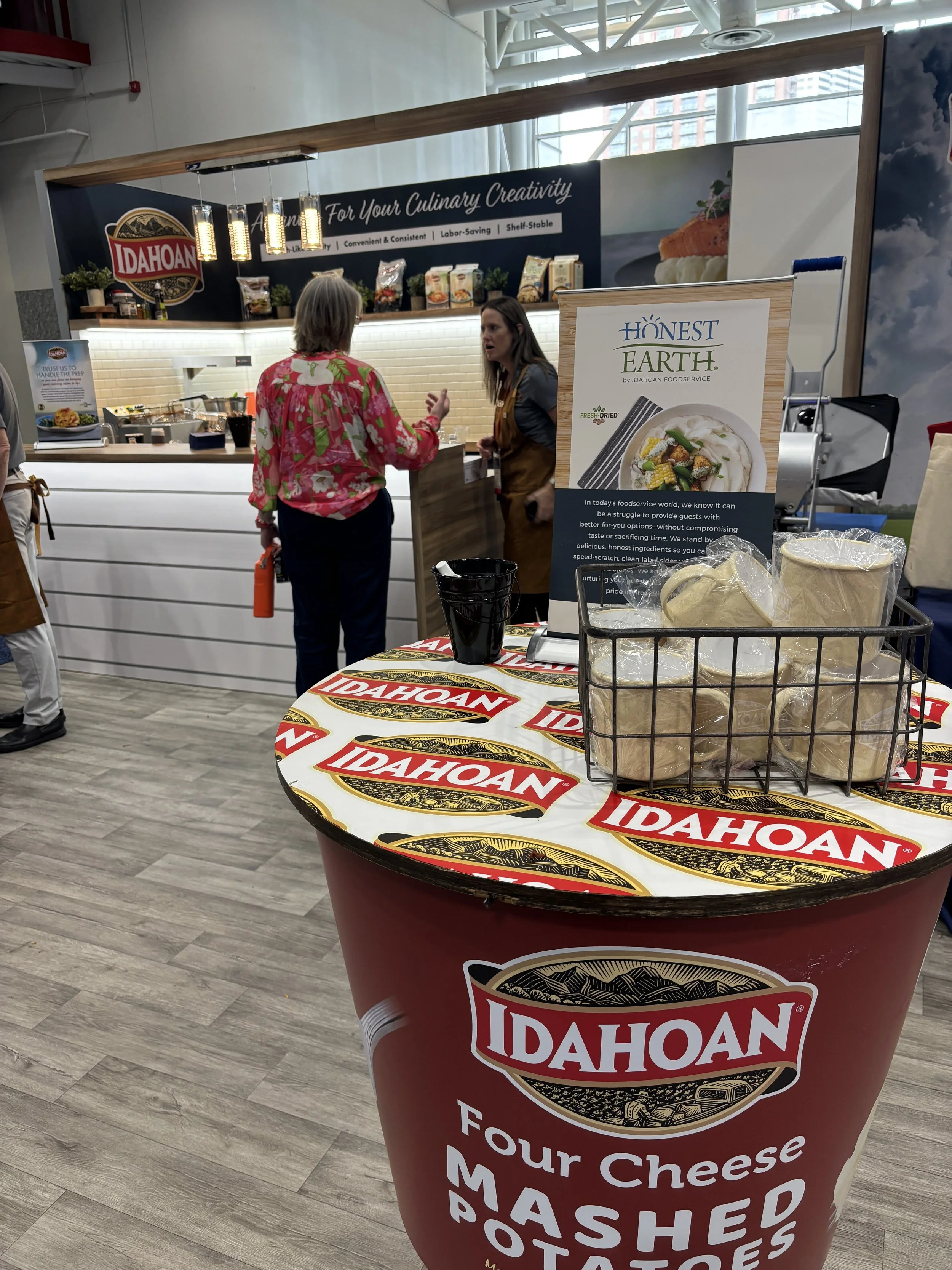 oversized microwavable cups as a tabletop, giveaway mugs and a pop up kitchen in background