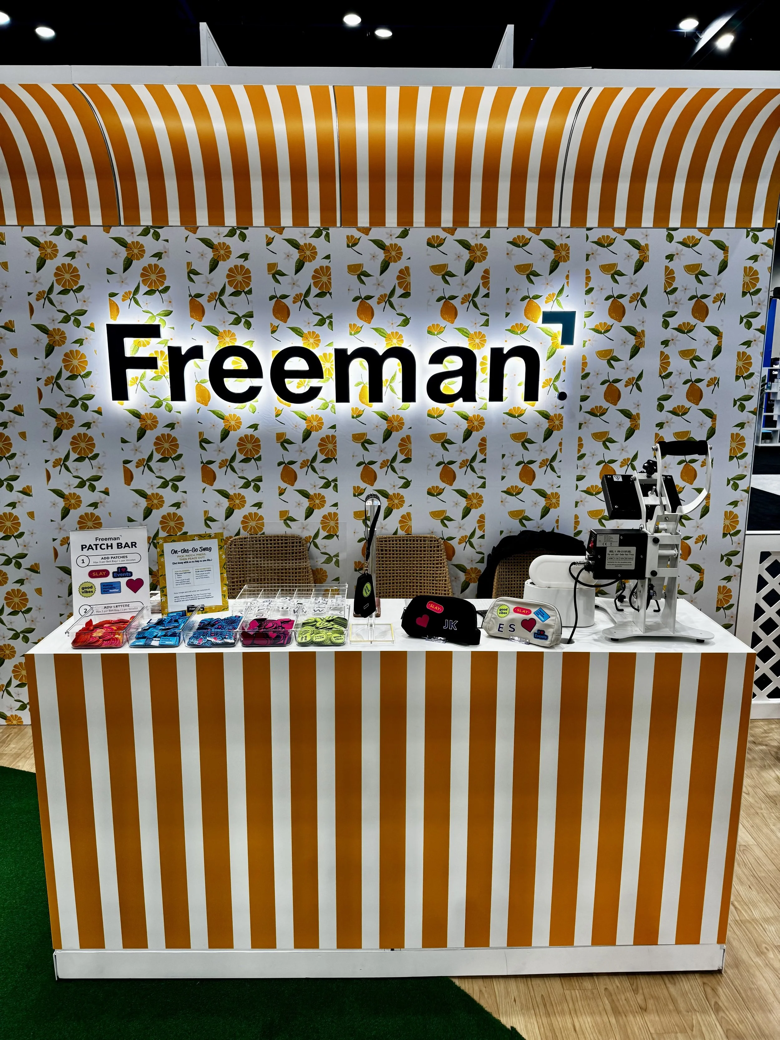 Colorful booth with patches laid out for guests to choose from and heat press ready to make customized belt bags and coin purses