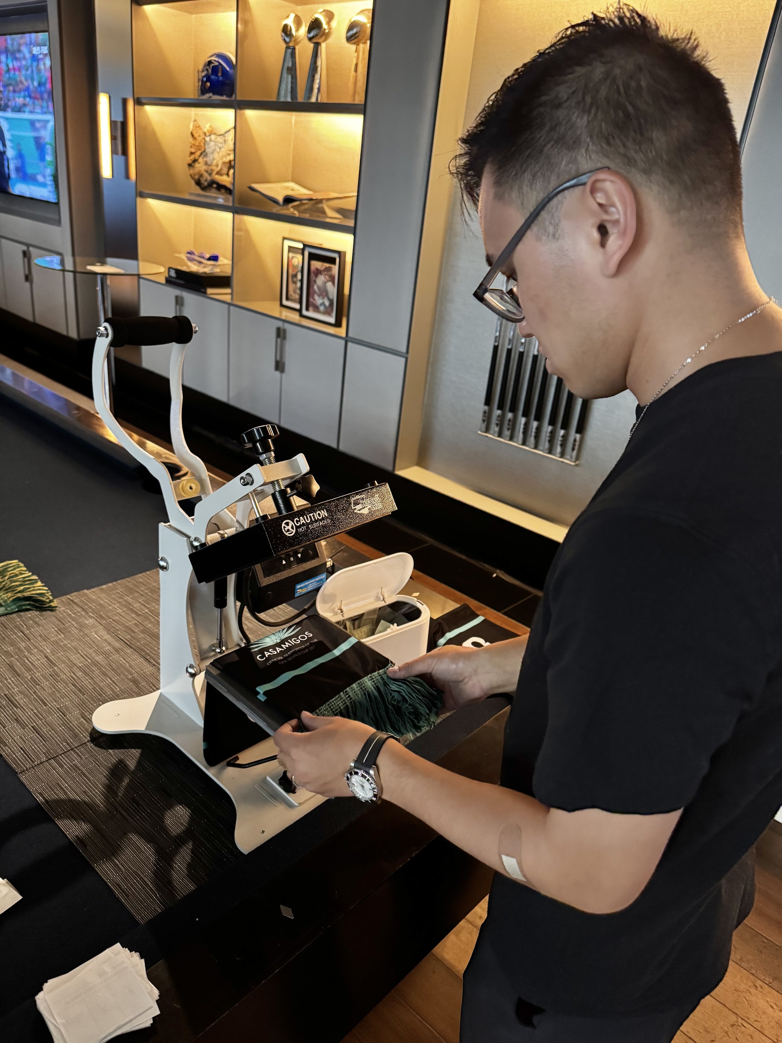 Apdat staff sets up the scarf on the press ready to apply monogram decals live on site