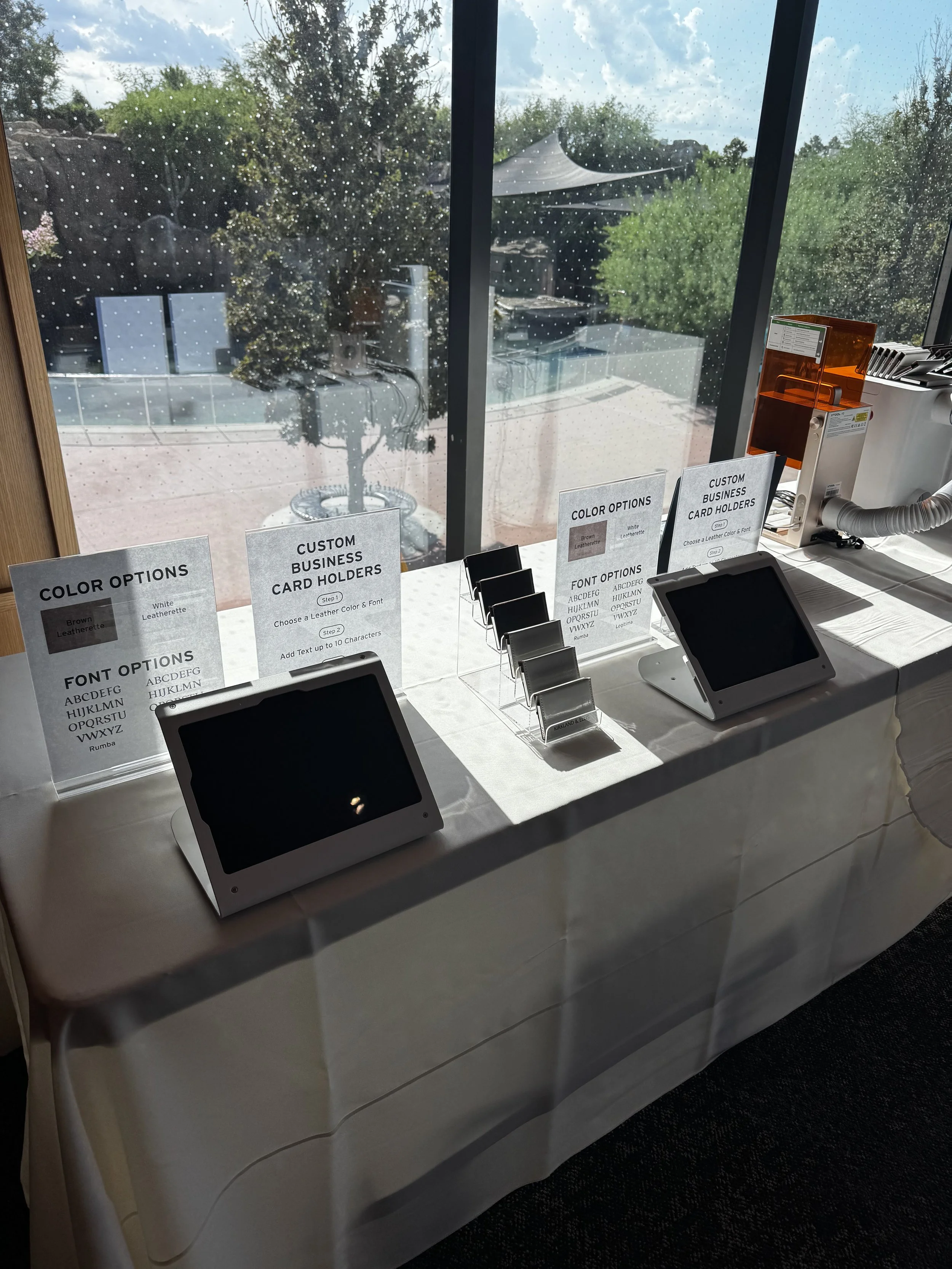 Wider angle shot of ipad station where guests select their business card holder color and font to have their names engraved live on site