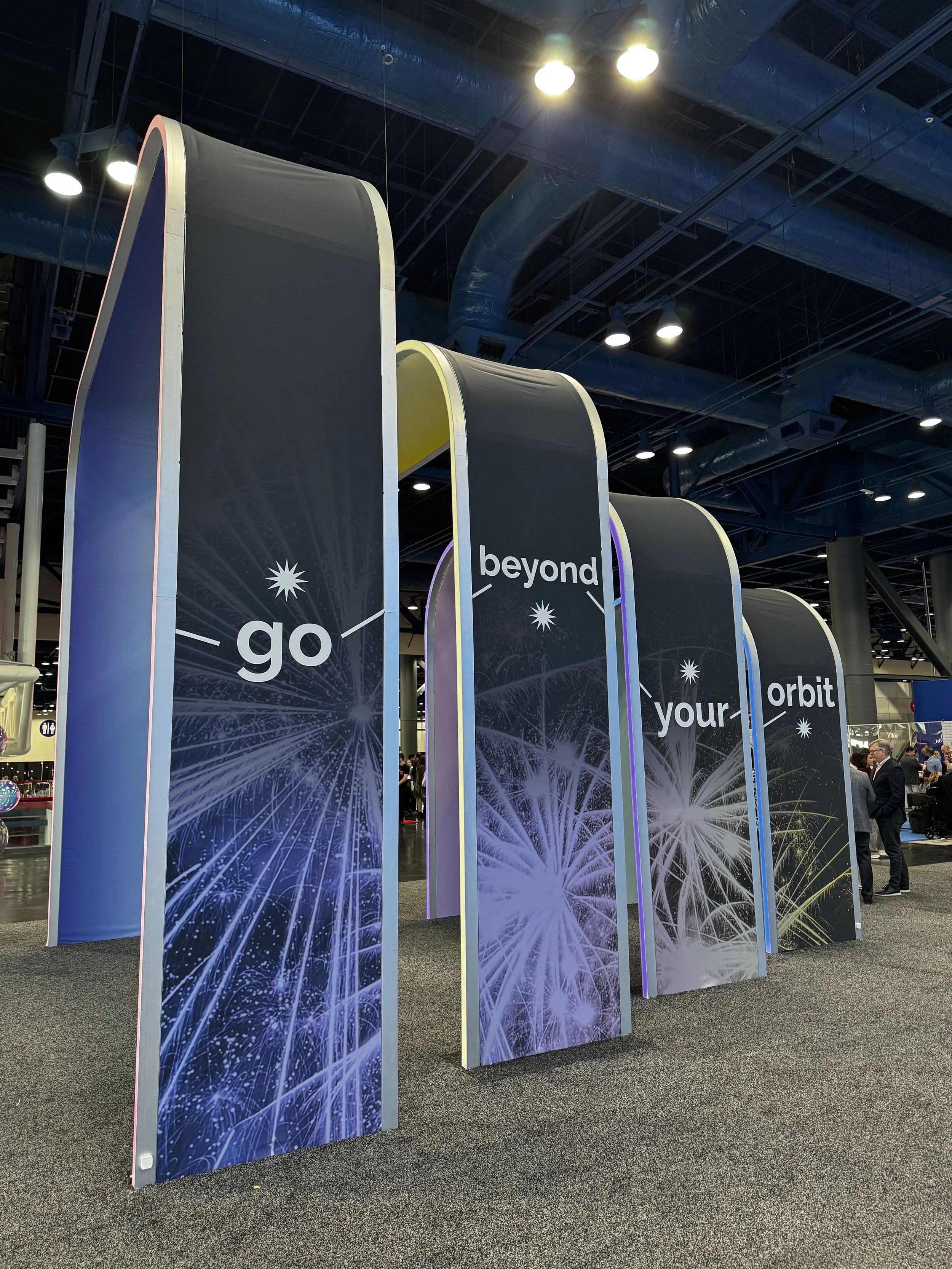 Archways that make up display at PCMA conference where apdat print co live heat pressed tote bags with houston and space themed decals.