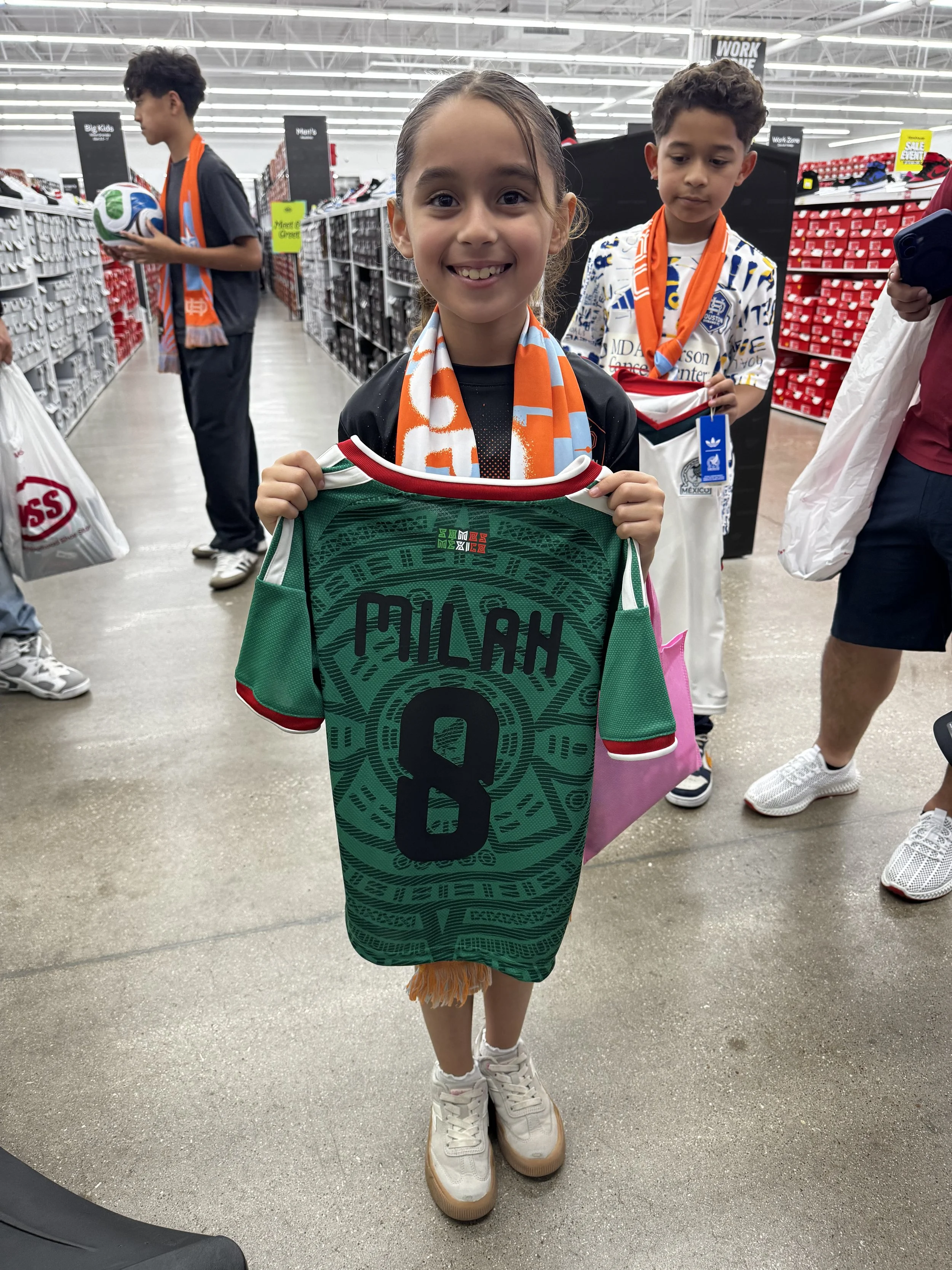 Child posing with her customized jersey while family waits for their turn