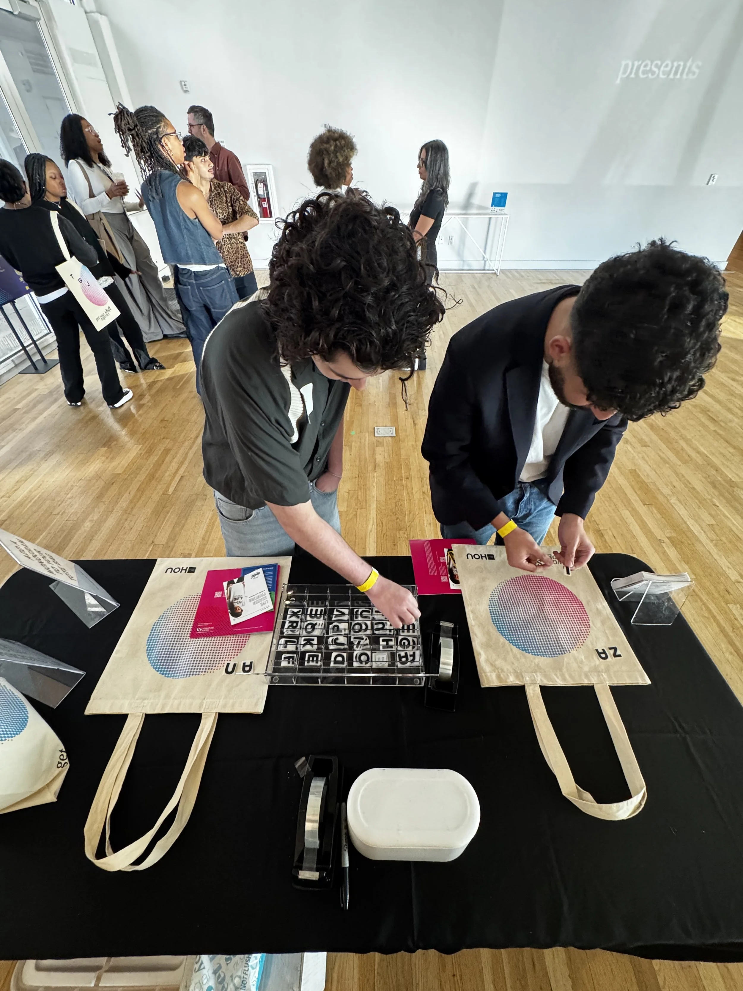 Two AIGA symposium attendees decorate their freshly printed tote bag with heat pressable decals