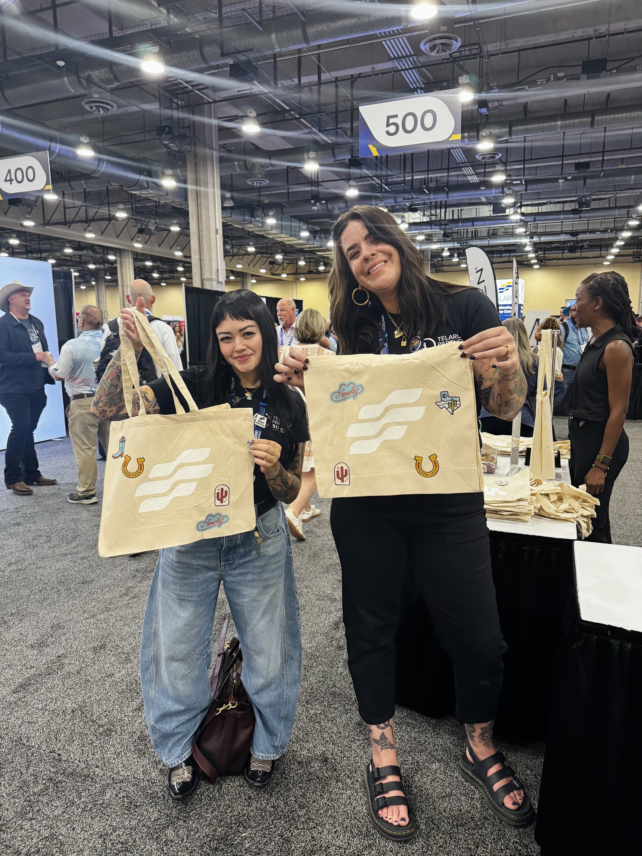 Attendees of the conference holding up their freshly pressed tote bags with western patches designed with Texas in mind