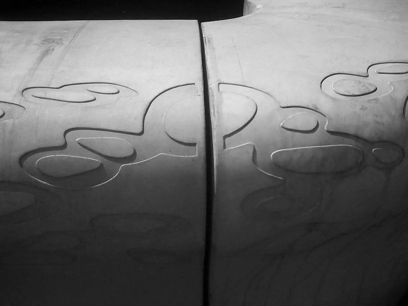 Close-up of a metallic surface with engraved doodle-like shapes and reflections.