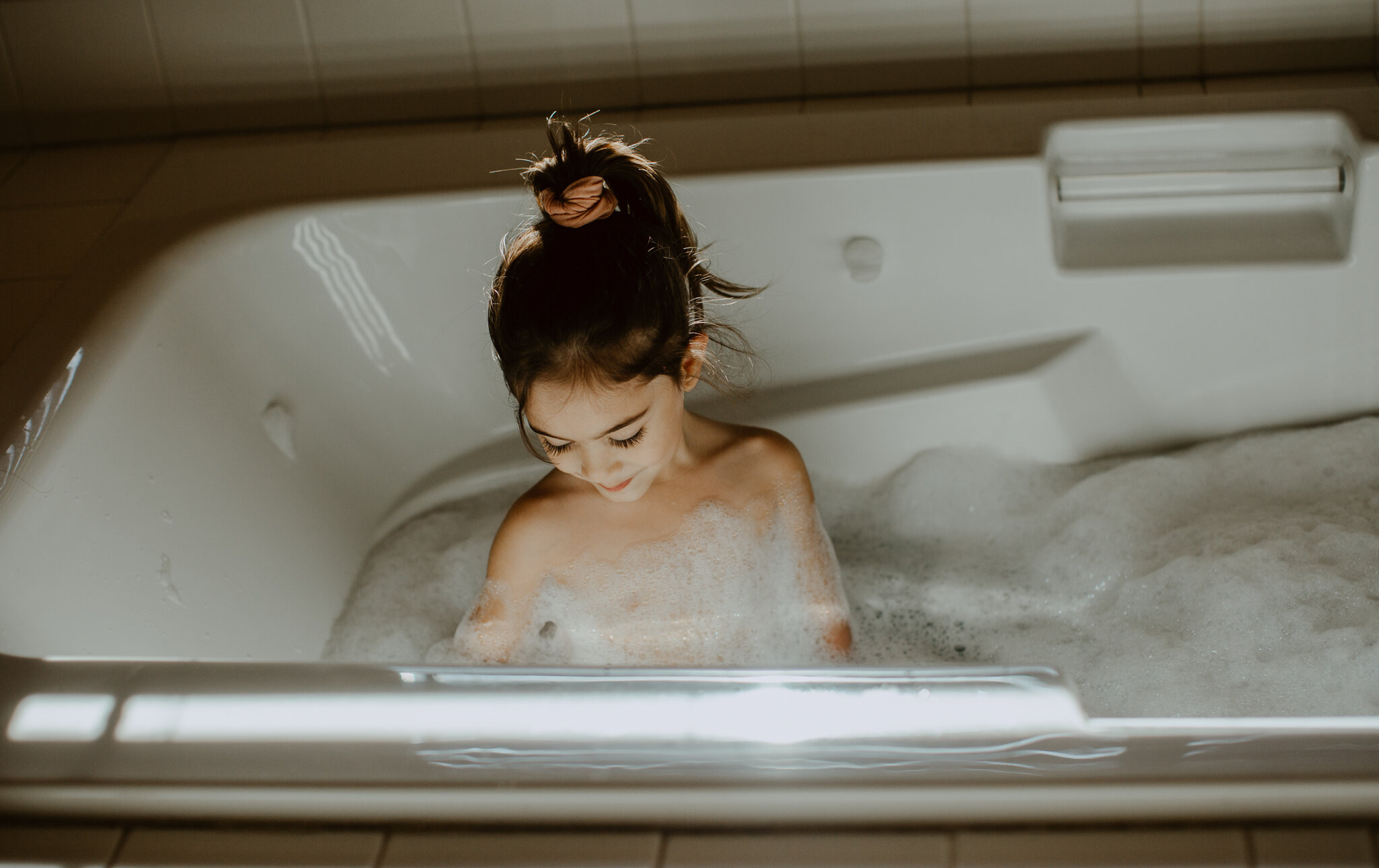 little girl in bath tub with bubbles