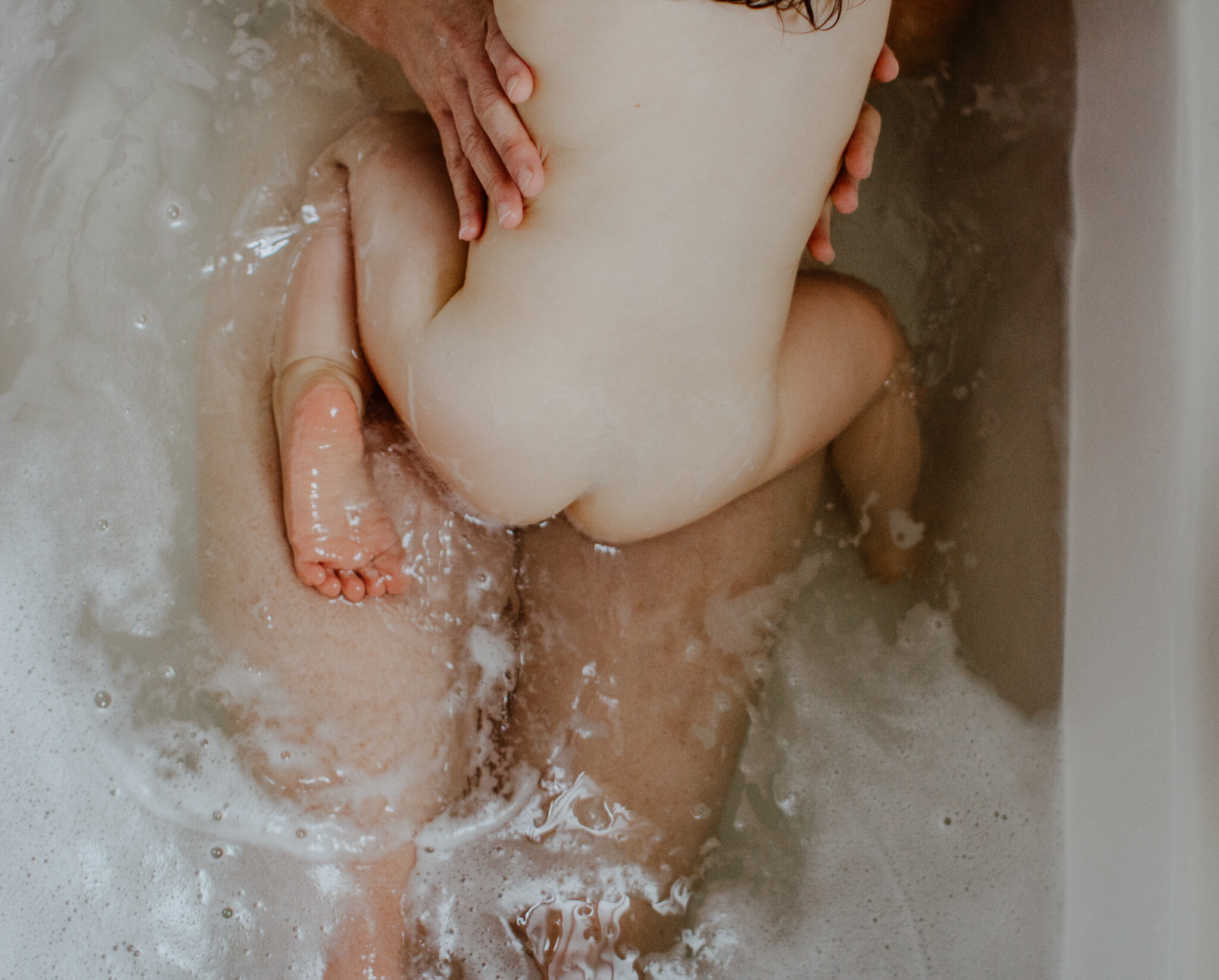 child in bathtub with mom