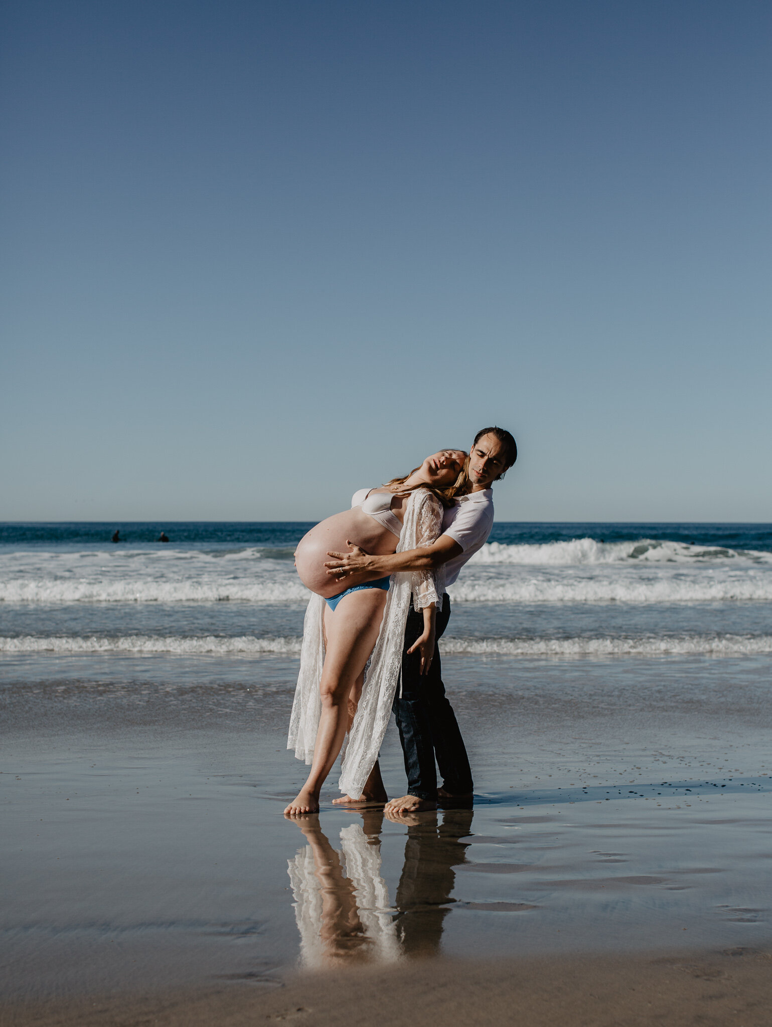 Pregnant mother dancing with husband on beach