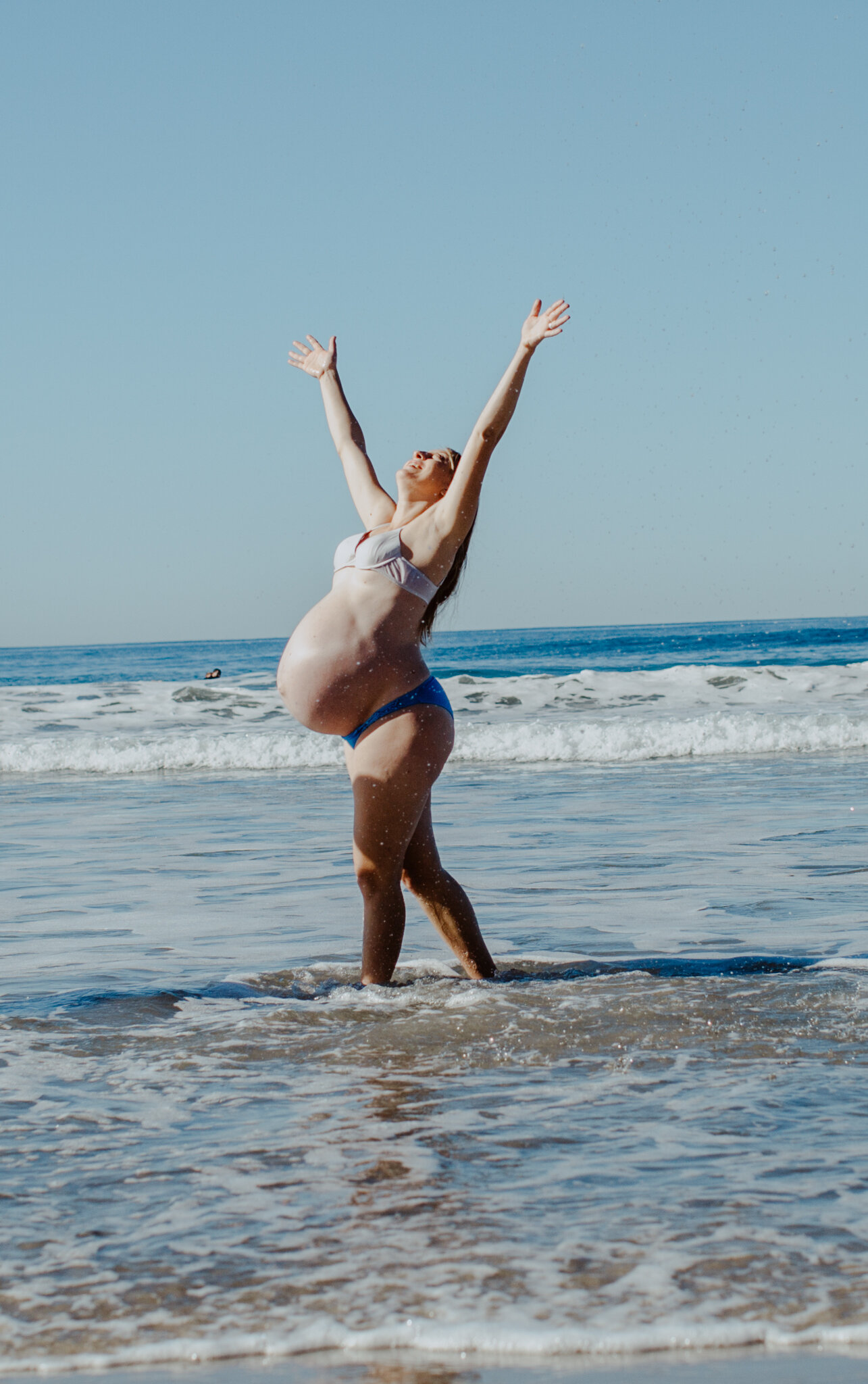 Pregnant woman dancing on beach and ocean