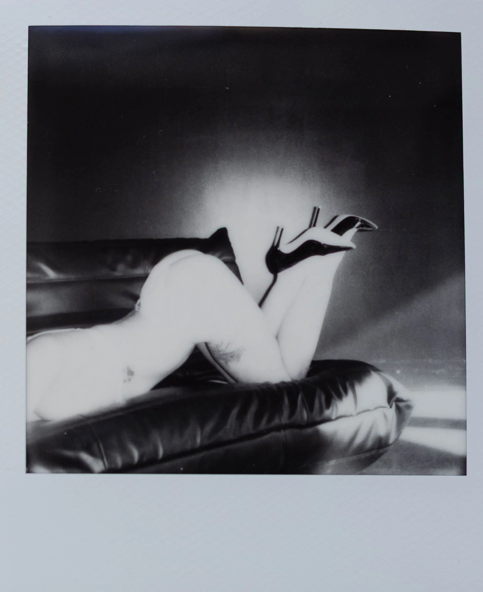 Black and white boudoir polaroid of woman's butt and heals in the air