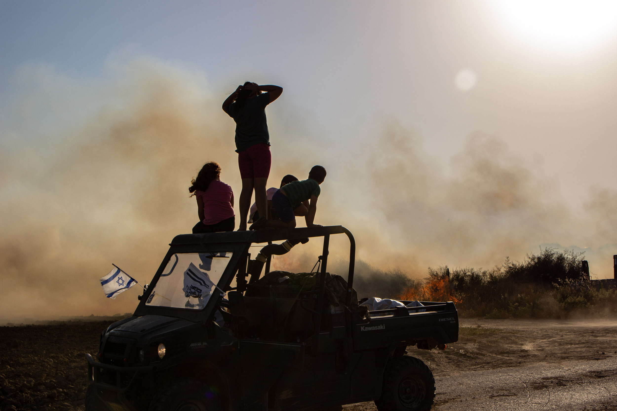 Northern Gaza Border, June 2018 - Kids from a nearby Kibbutz watching they fields set on fire by a burning kite sent from Gaza
