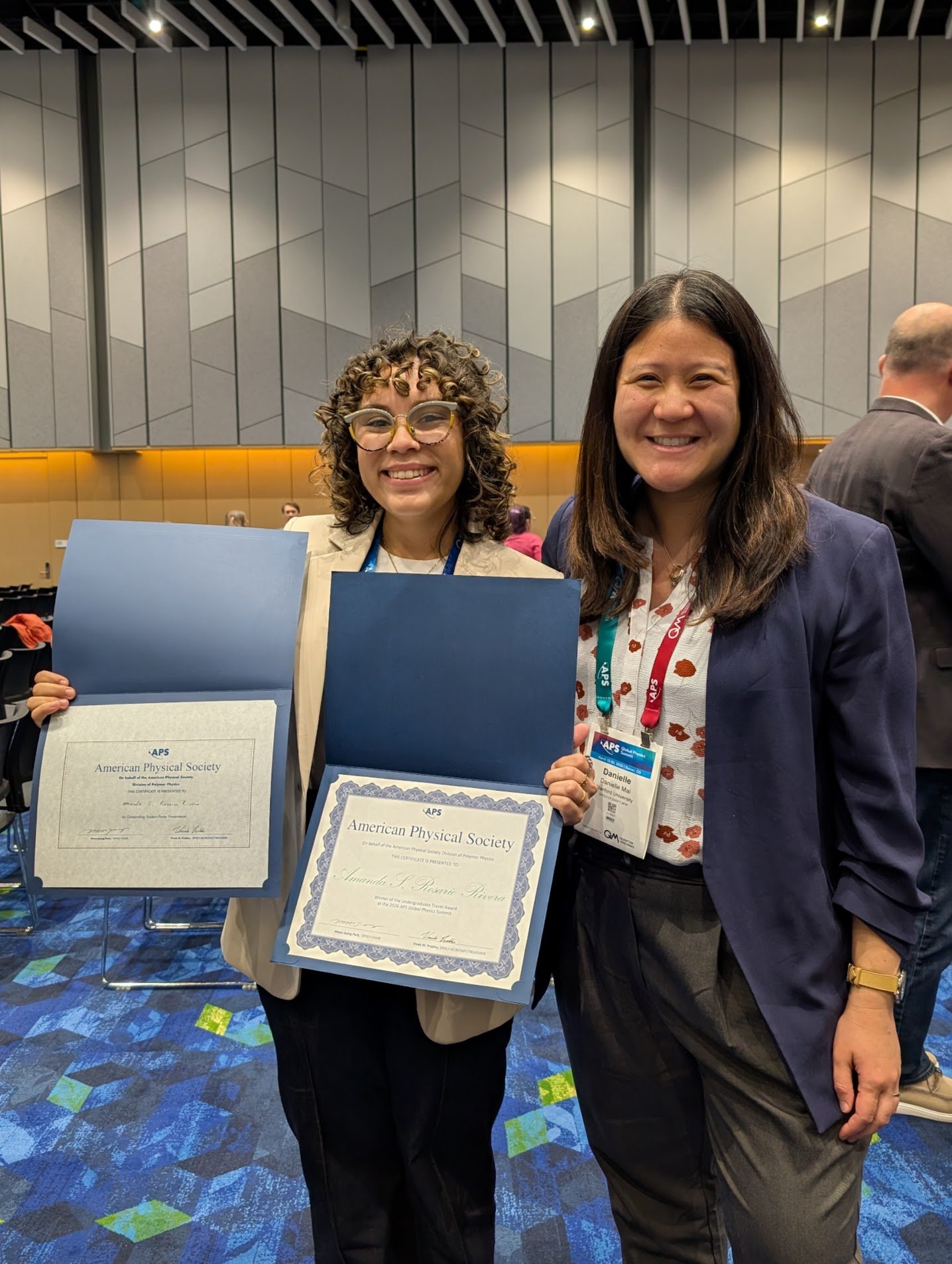 Amanda with certificates for the DPOLY undergraduate travel award and the DPOLY student poster award