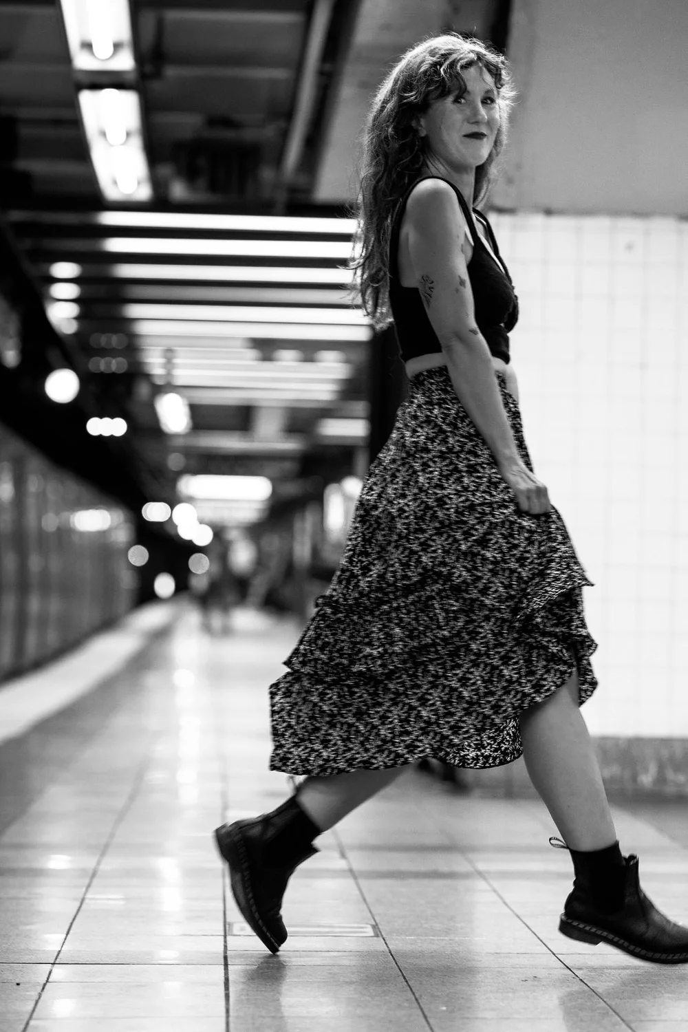 Elizabeth Laura Nelson walking along a New York subway platform, black and white
