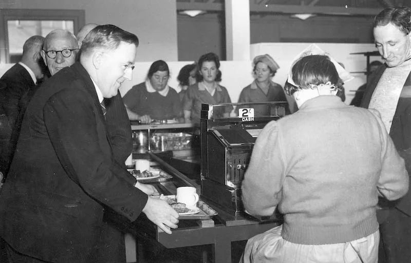 Minister for Shipping and Supply, Mr. Beasley, smilingly pays [one shilling and three pence] for steak and kidney pudding and a cup of tea, Glebe Island 1940-1945