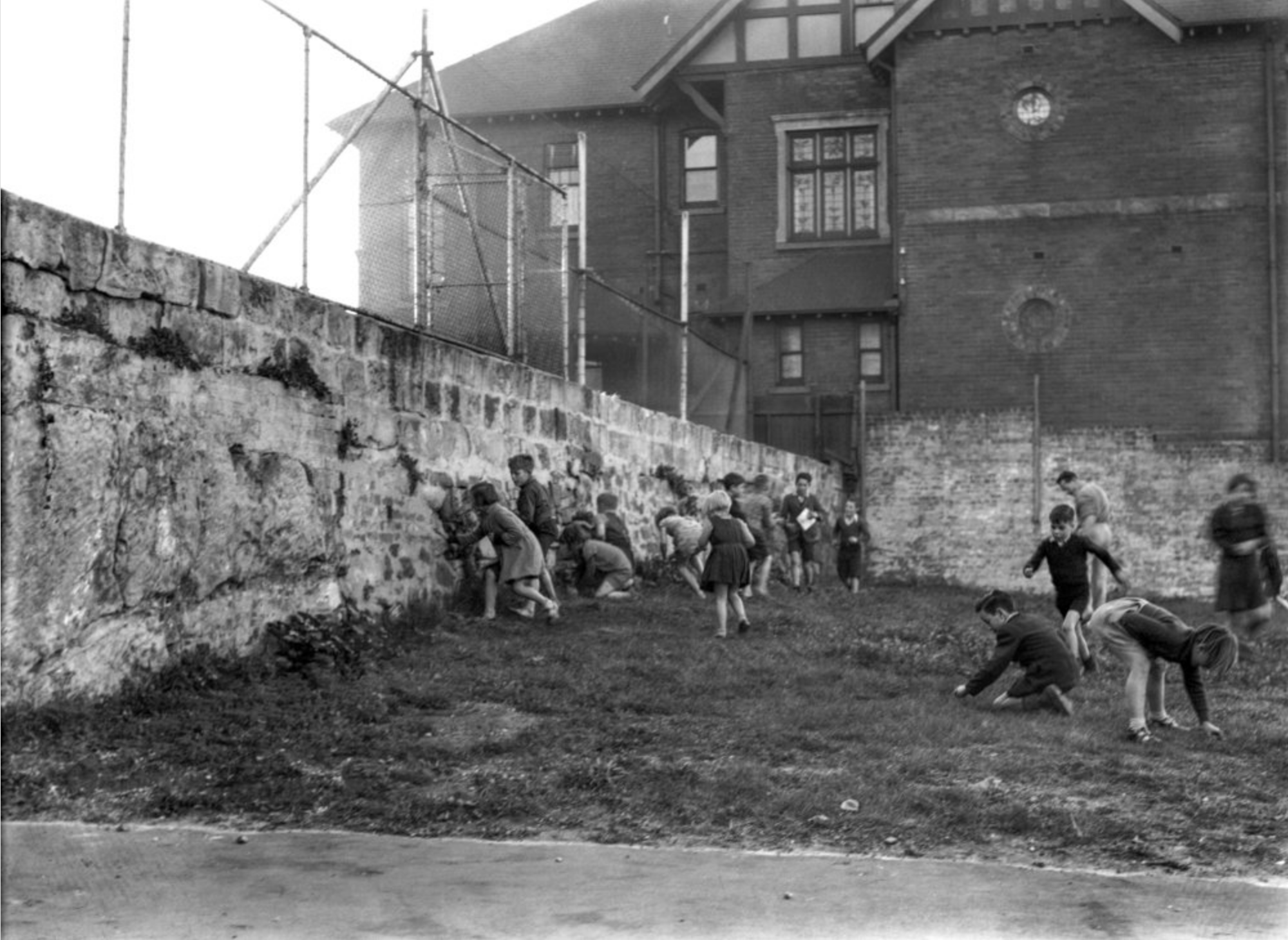 Children playing along the wall in Maybanke playground with CSR hostel at rear, 1930