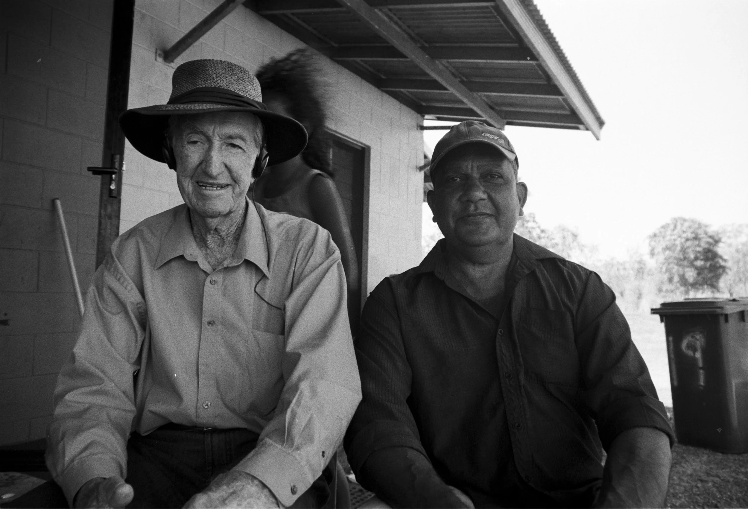 Ronnie, Community leader outside his home, sitting for a portrait with his father 