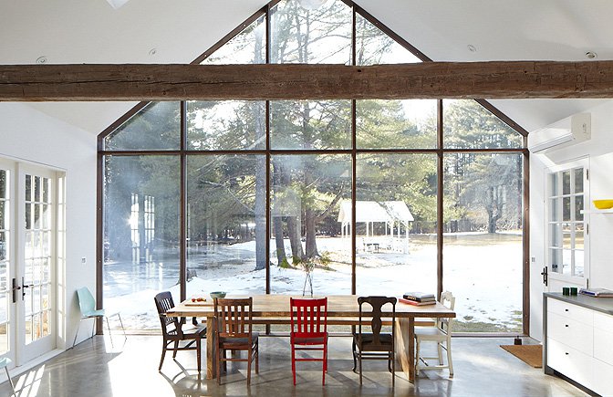 Modern custom home interior with polished concrete slab flooring, floor-to-ceiling glass walls, exposed structural beam, and open dining area by Overlook Building Inc.