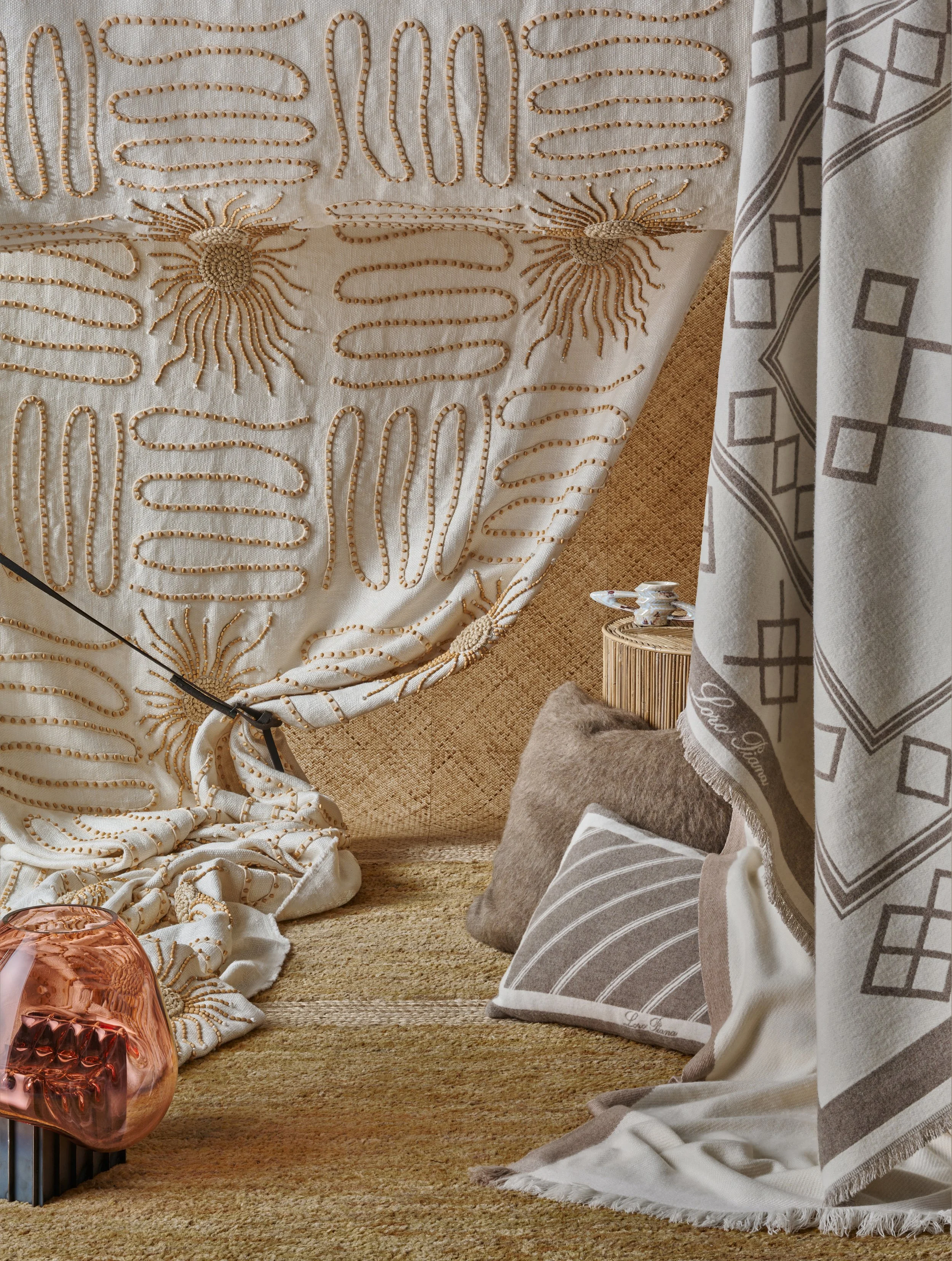 Cozy interior corner with embroidered fabric, pillows, and a small side table with a decorative object, soft lighting, and warm tones.