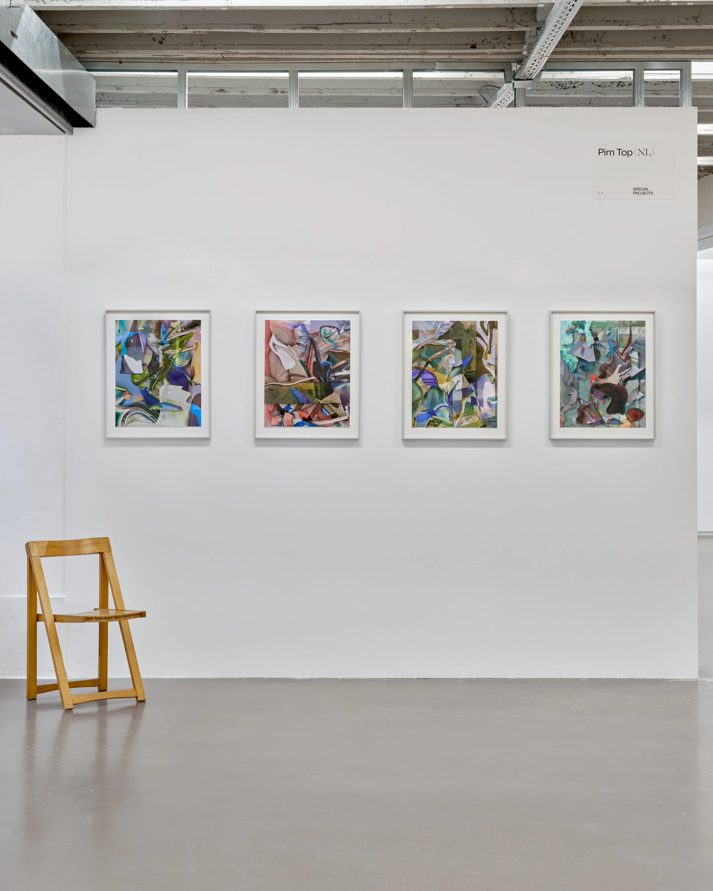 Empty art gallery with four colorful abstract paintings on a white wall, a wooden chair, and visible metal and concrete ceiling.