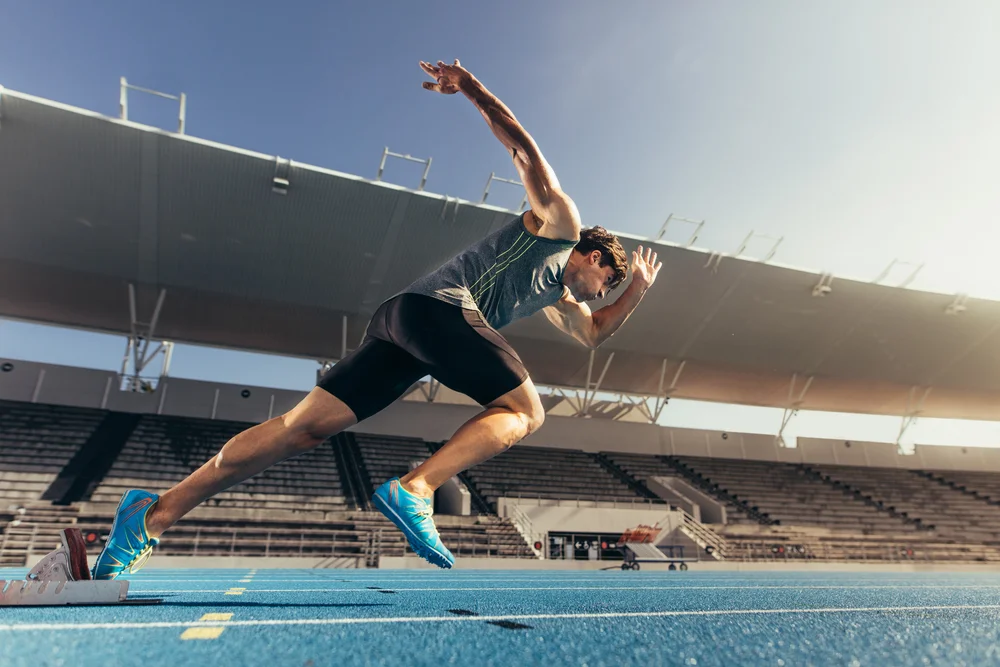 Athlete using starting block to start his run on running track in a stadium.jpg