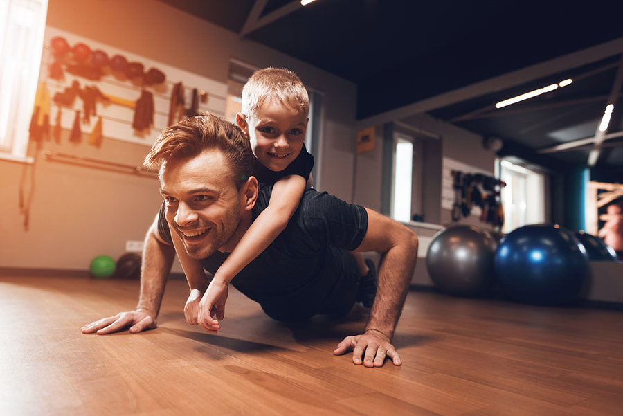 man doing pushups with son on his back