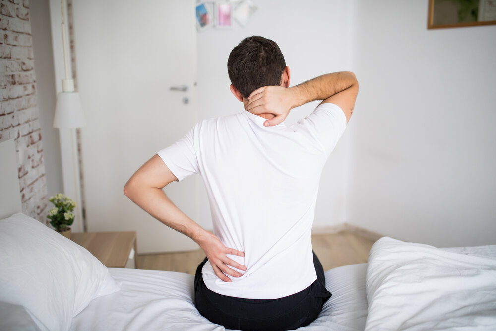 Man suffering from back pain at home in the bedroom
