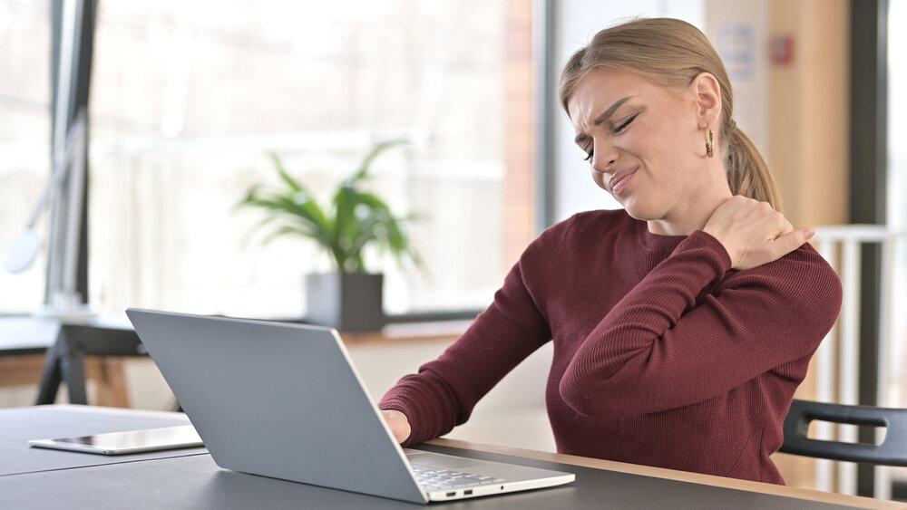 Tired Young Woman with Shoulder Pain Working in Office