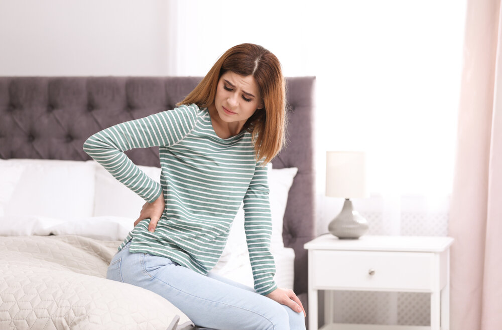 Young woman suffering from back pain at home