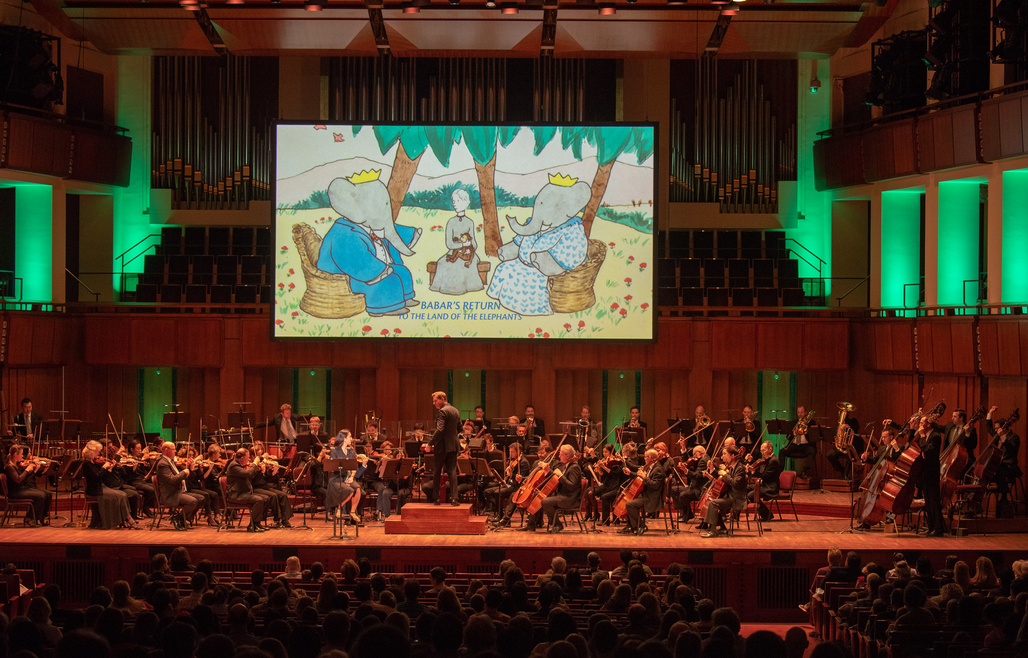 First U.S. performance, Babar’s Return to the Land of the Elephants National Symphony Orchestra, Steven Reineke, conductor, Regina Aquino, narrator, John F Kennedy Center for the Arts, Washington, D.C., April 7, 2019 Photo: Erica Bruce (full size photo available). Multimedia image: original Jean de Brunhoff watercolor, Kendra & Allan Daniel Collection. Used with permissions