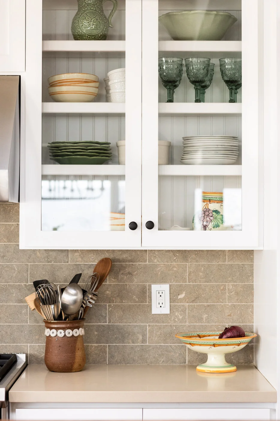 Coastal Craftsman kitchen with custom white painted shaker cabinets and glass door panels
