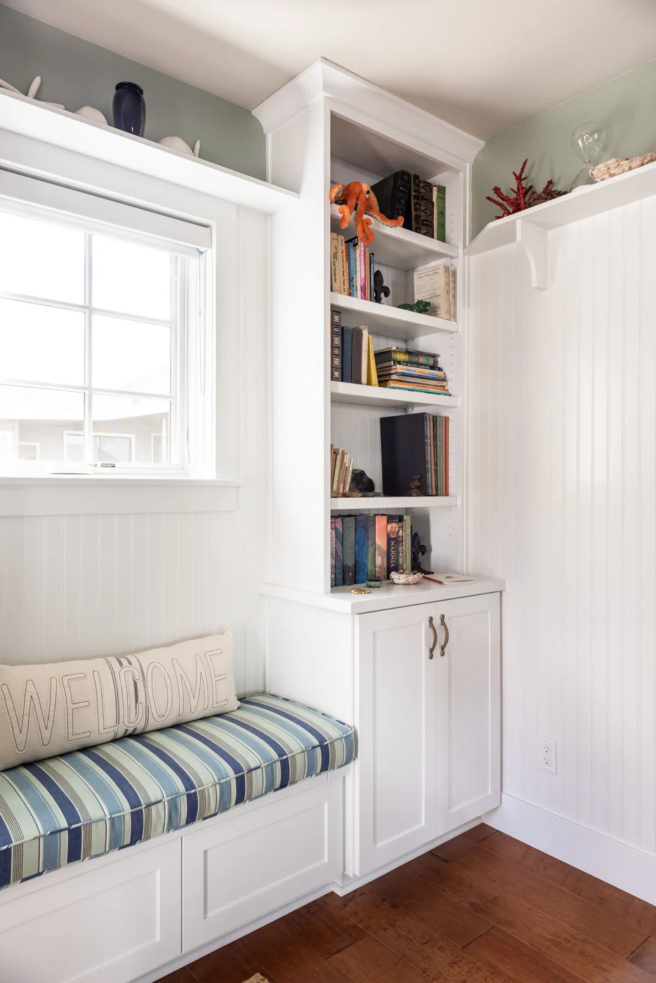Coastal Craftsman home with custom white painted built in bookcase cabinets shelving