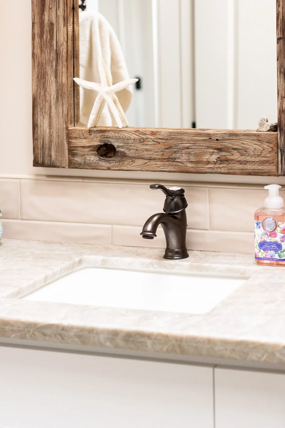 Coastal Craftsman home with custom white painted bathroom vanity cabinets and stone counter tops