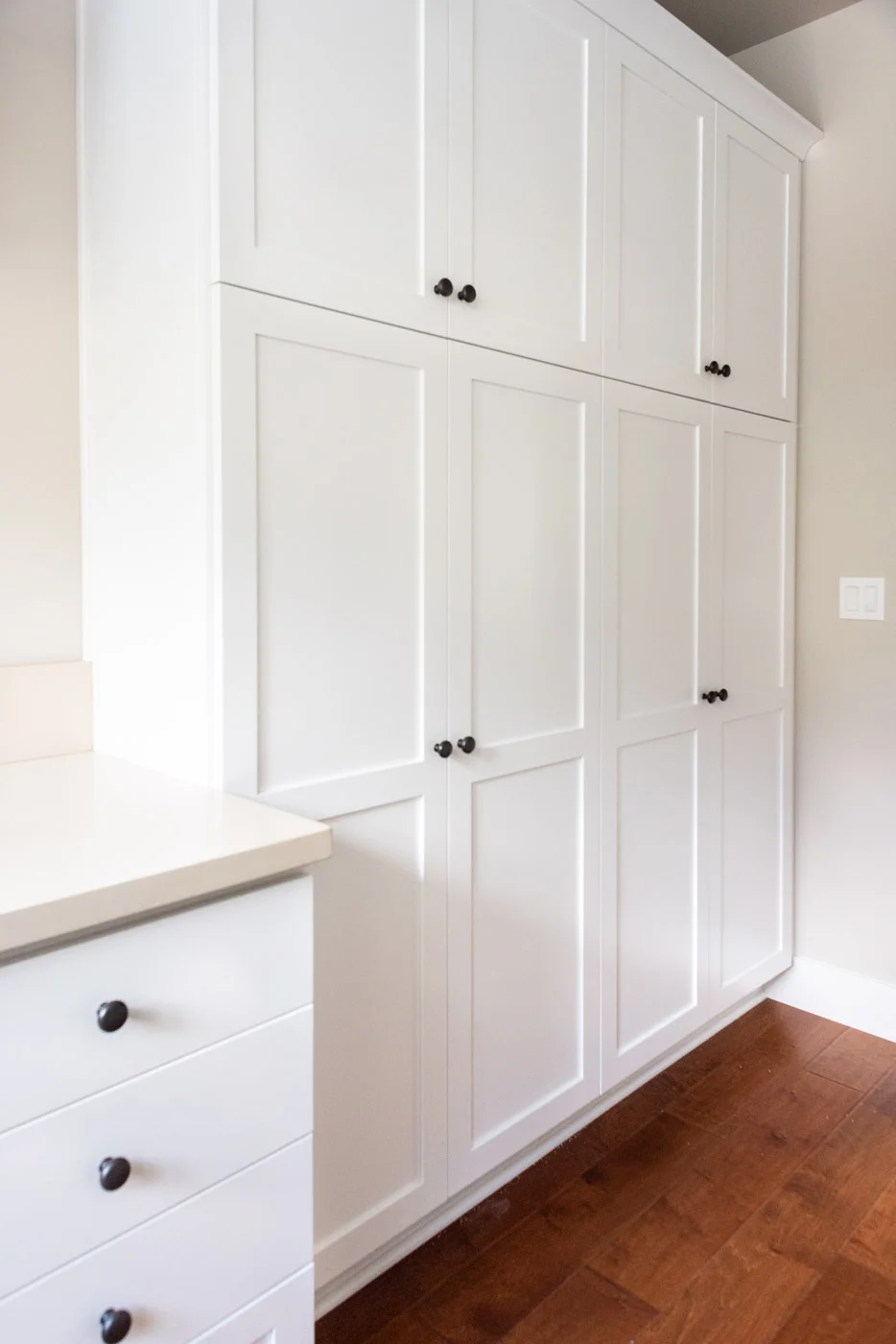 Coastal Craftsman home with custom white painted laundry room linen closet cabinets