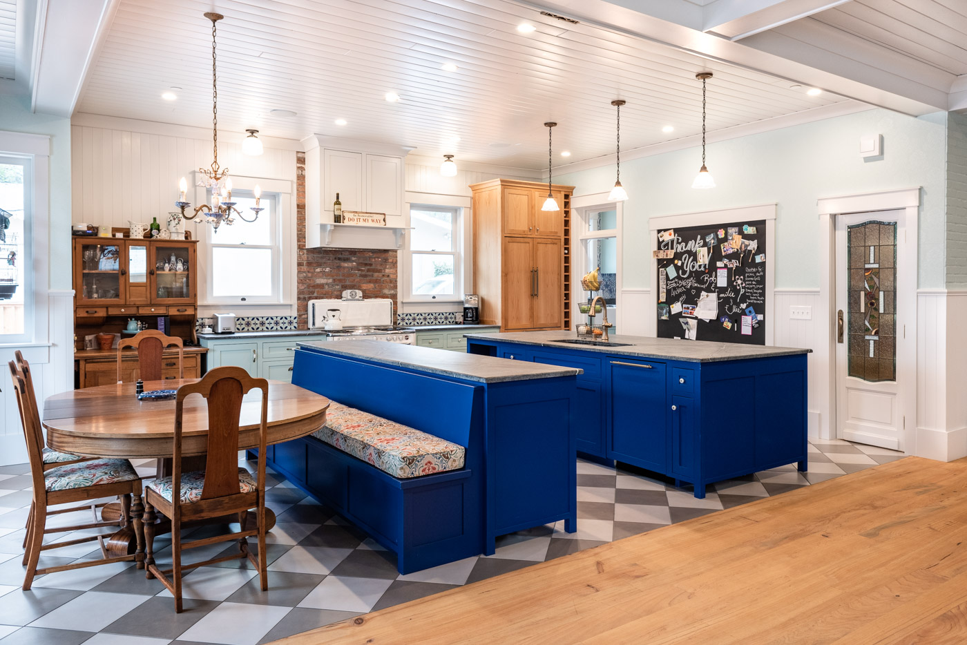 An expansive kitchen/dining area with a U-shaped layout using multiple kitchen islands