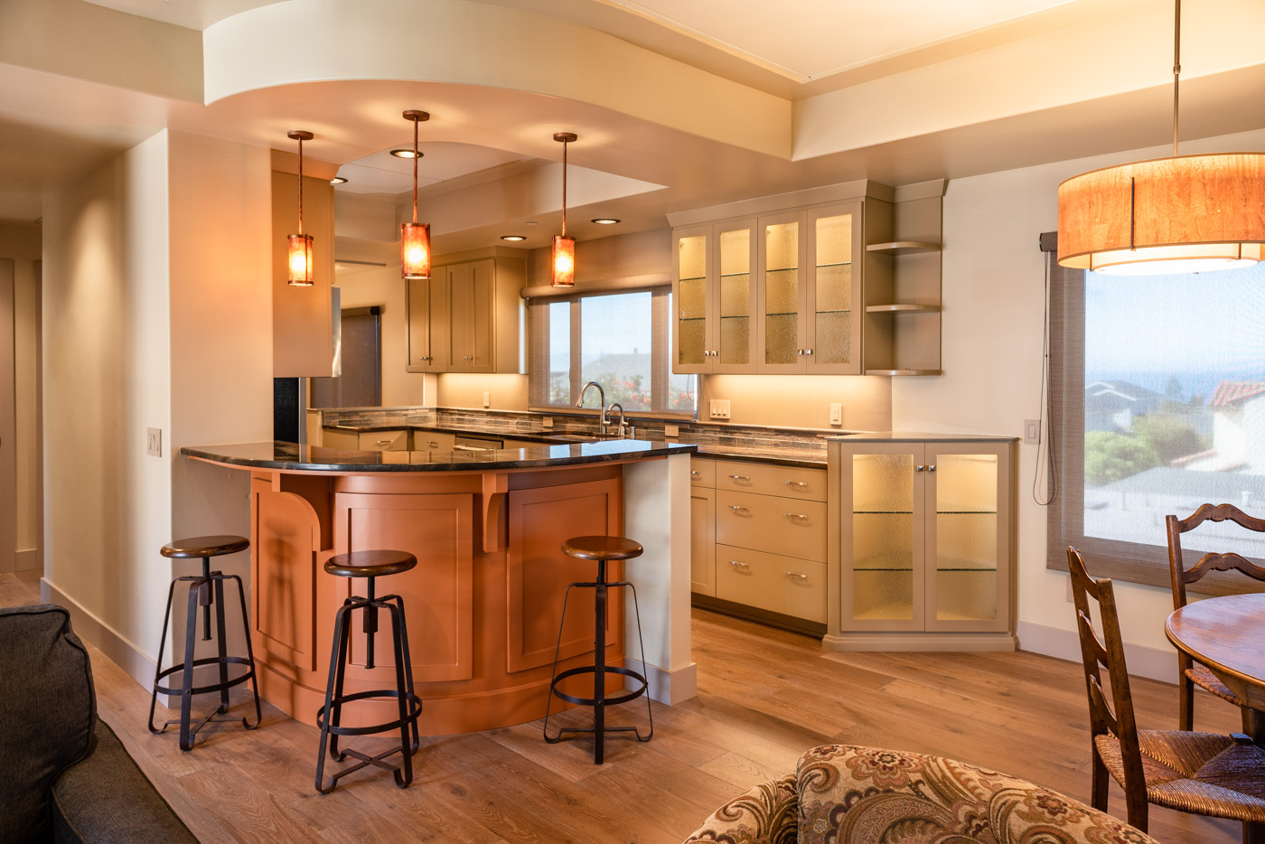 A G-shaped kitchen layout with custom orange and beige painted cabinets