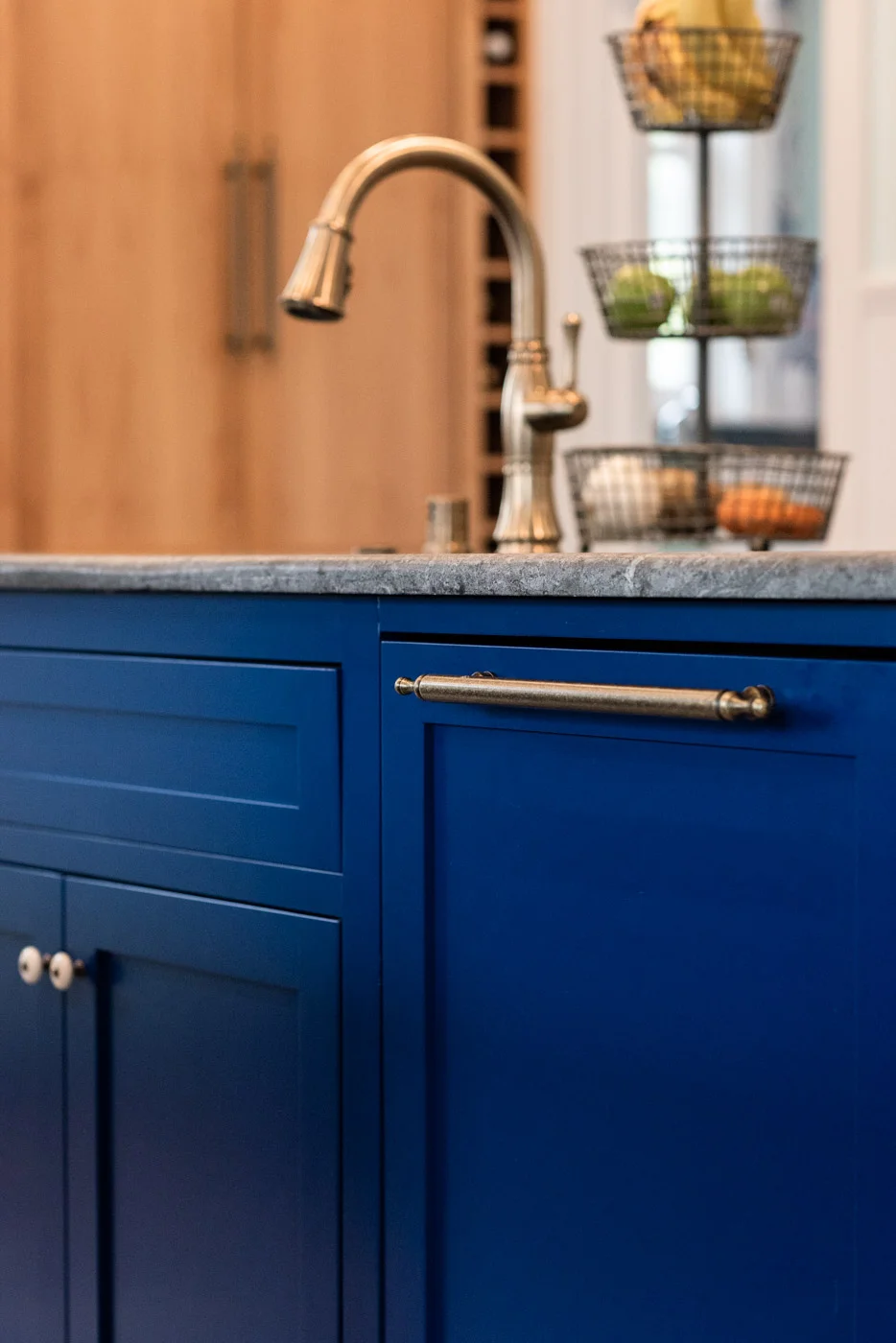 A mix of knobs and bar pull kitchen cabinet hardware in a brass finish against blue custom painted cabinets