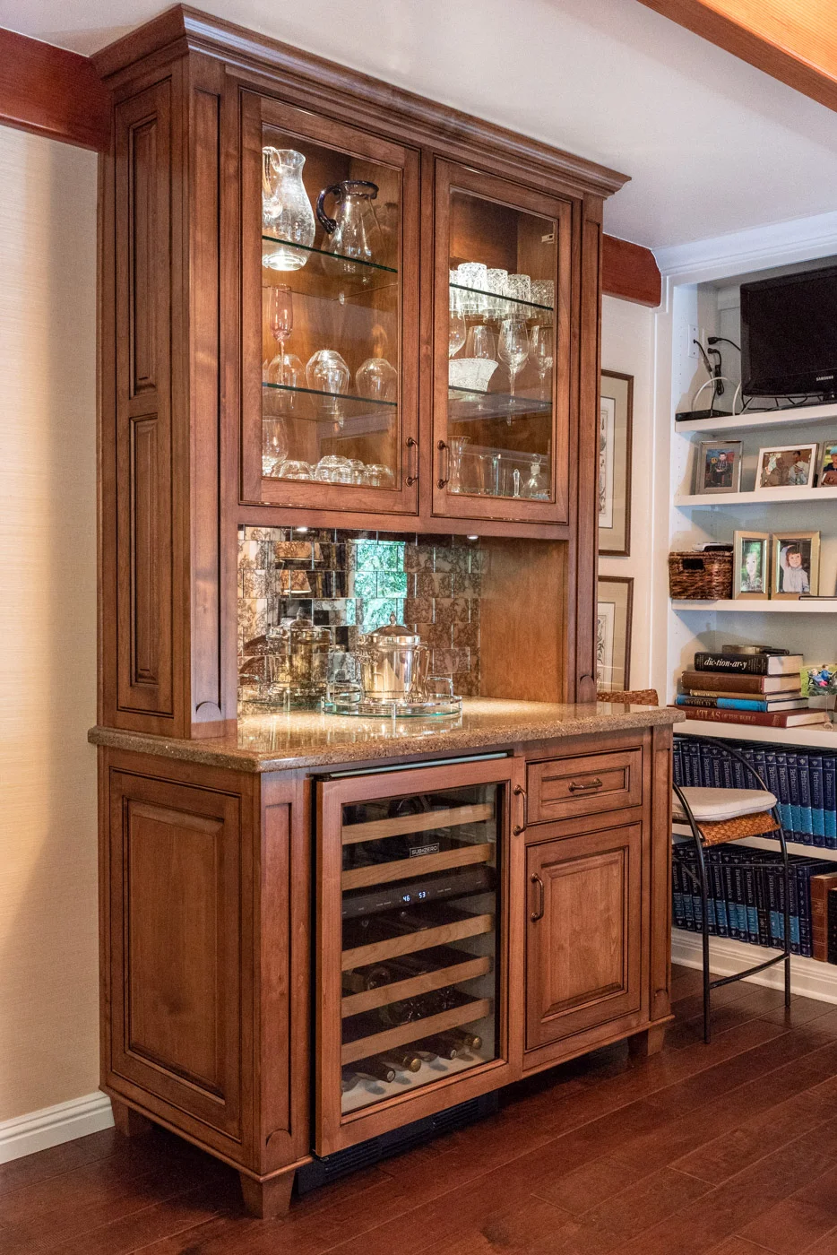English Country custom home bar with glass display cabinets and wine fridge