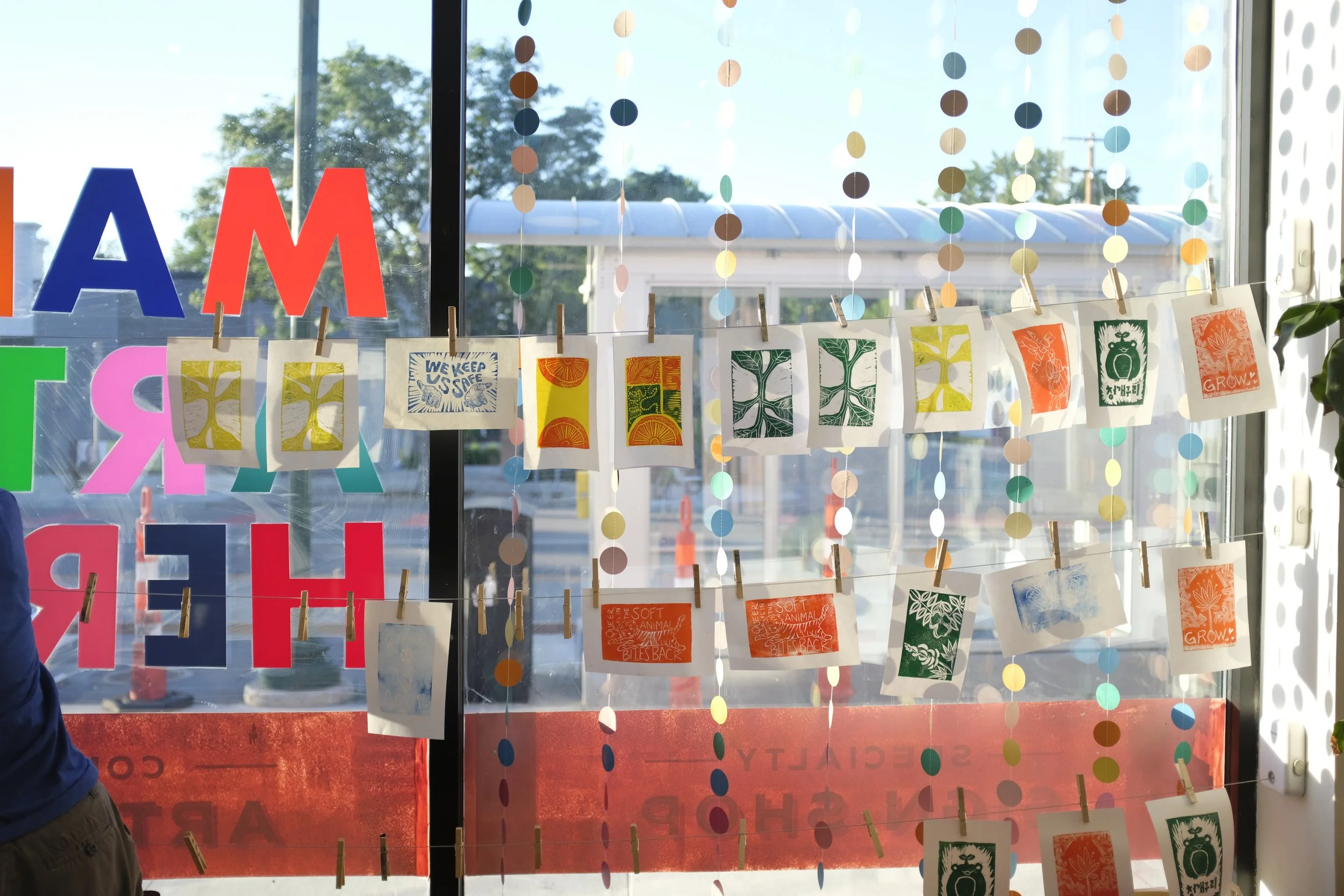Relief prints hung from clothesline on window to dry.