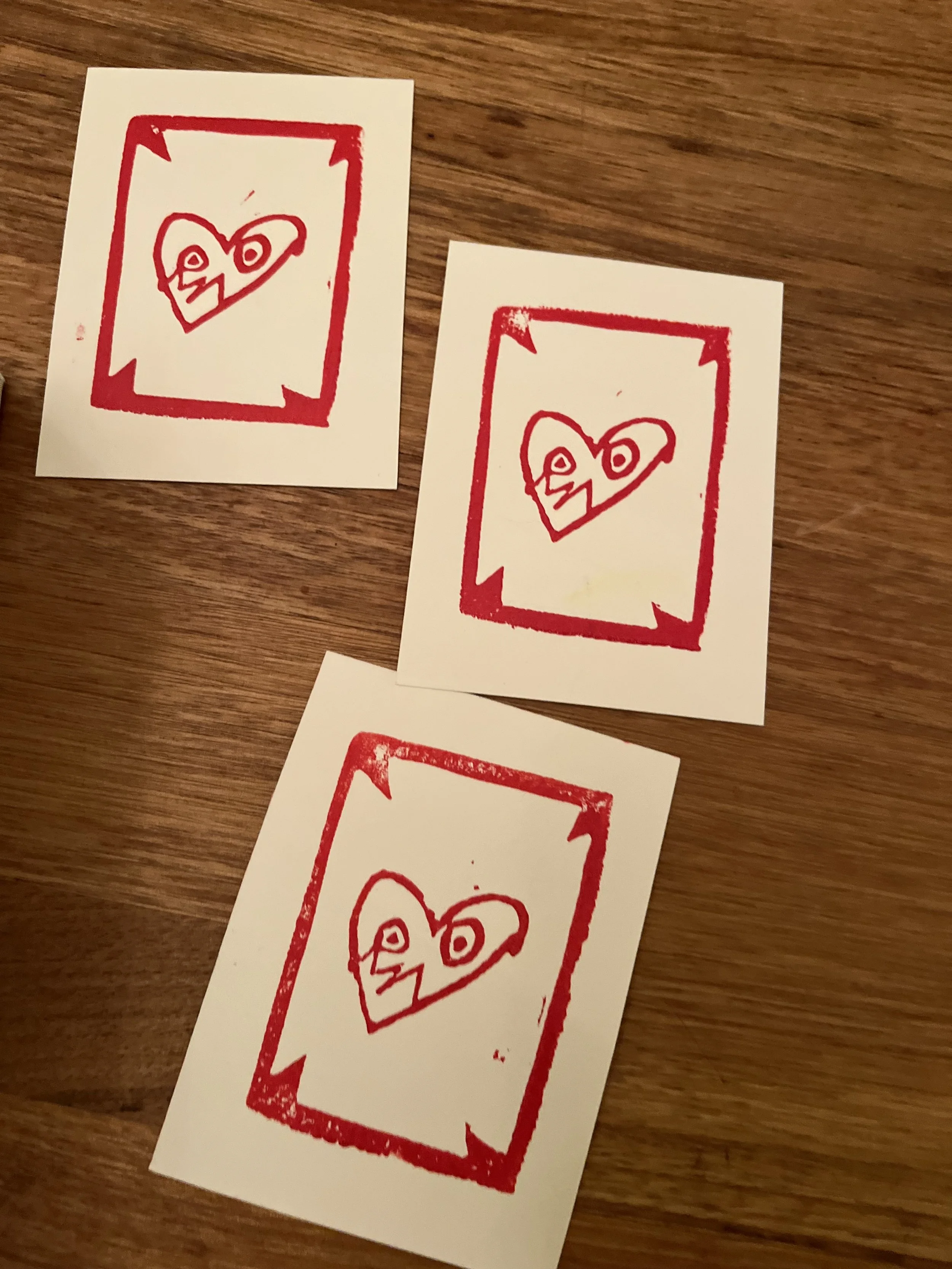 3 copies of relief printed image depicting a heart with a face and a border in red ink on white paper (Copy)