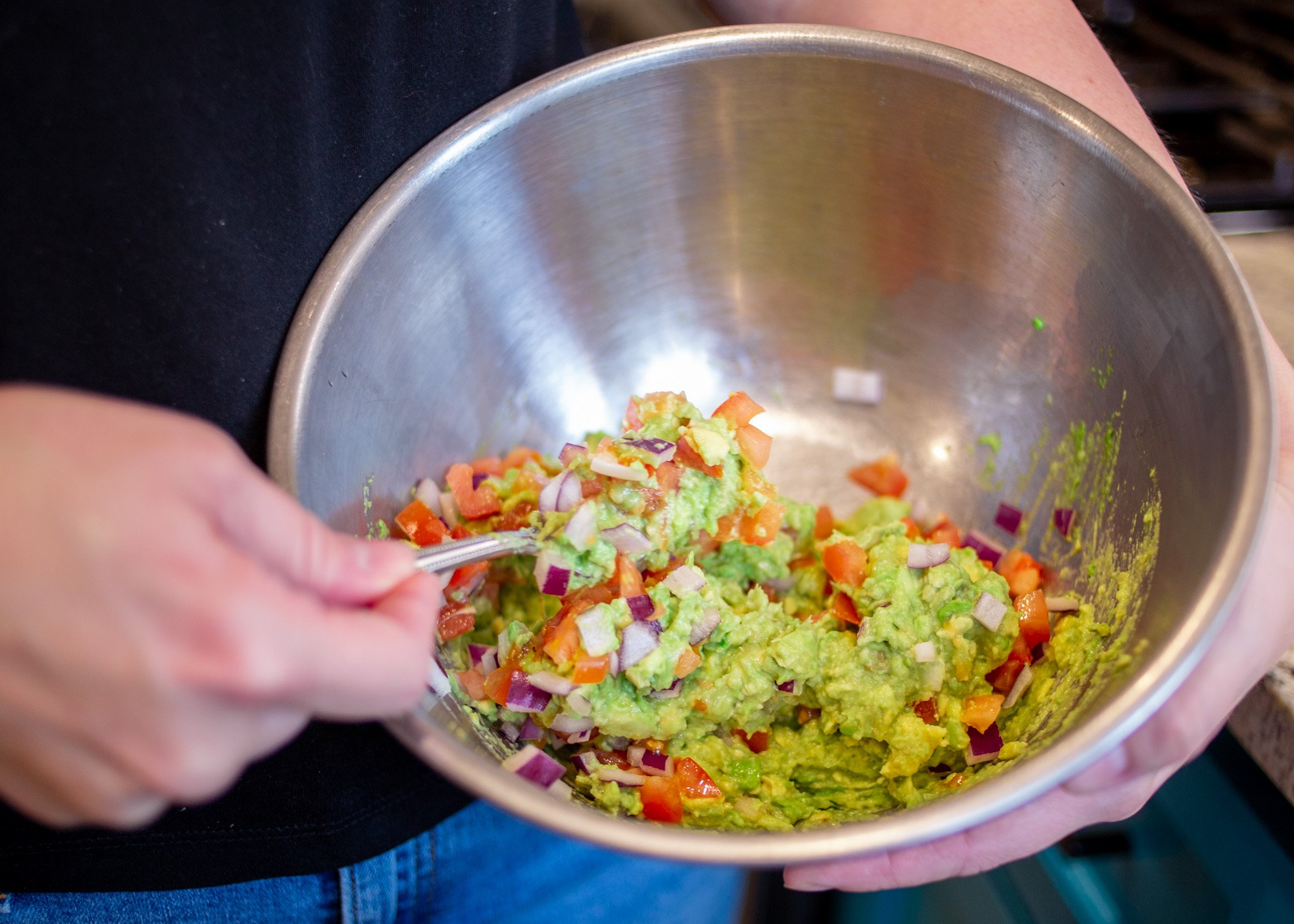 A mizing bowl filled with fresh guacamole ingredients.