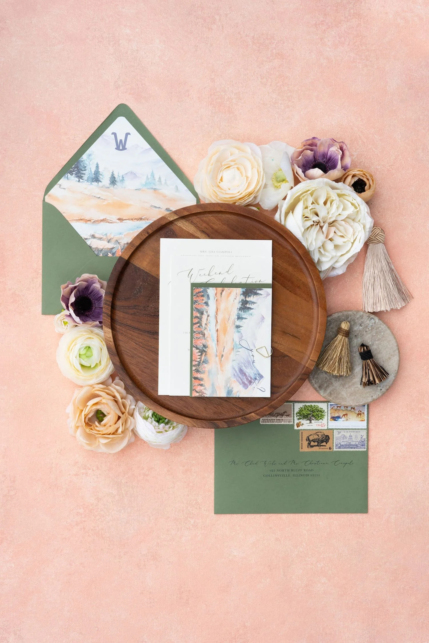 Luxury mountain ranch wedding invitation suite featuring watercolor autumn mountain landscapes, peach and sage color palette, modern script typography, handmade paper, and Western-inspired details arranged in an elegant flat lay.