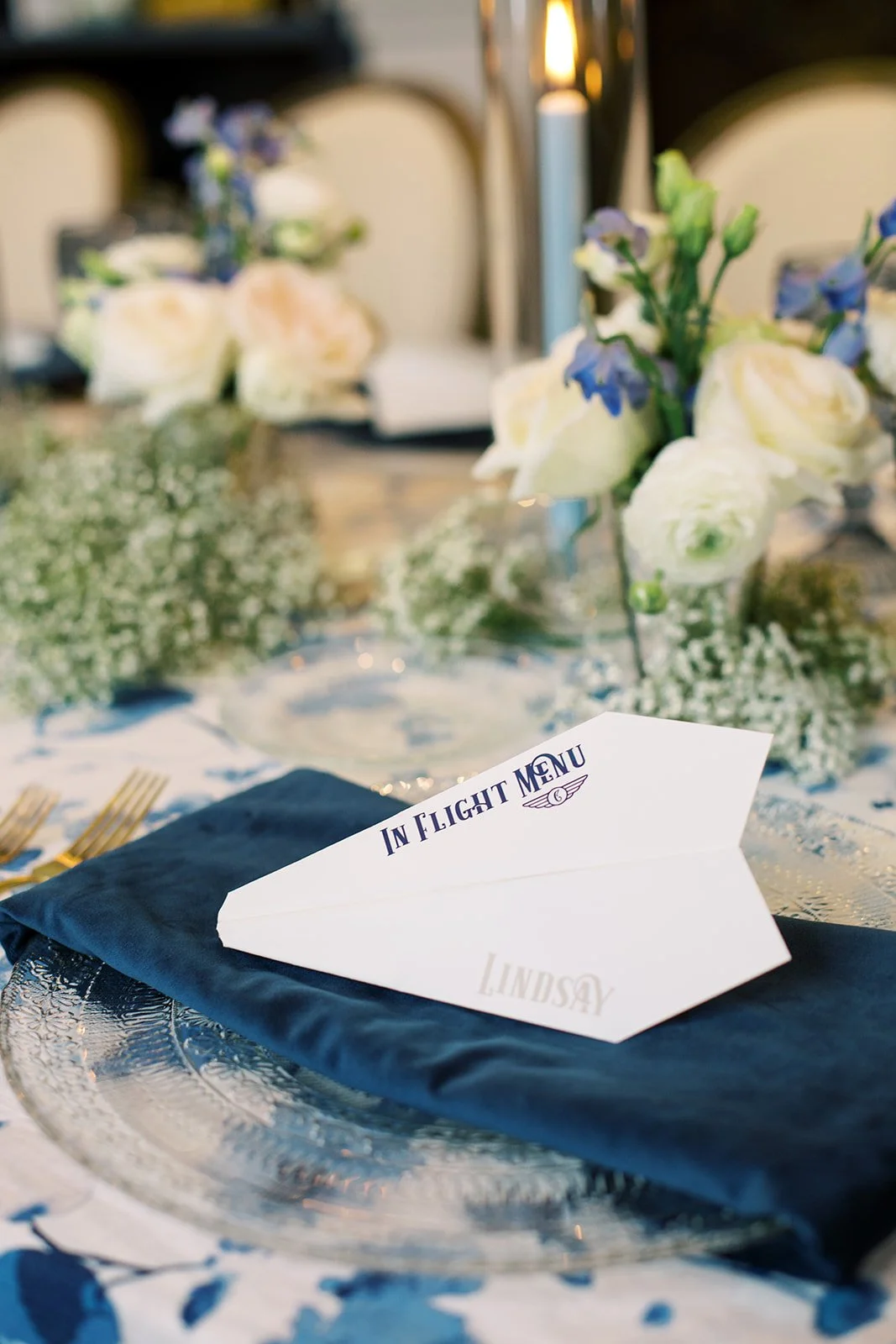 Paper airplane-inspired menus featuring modern typography in navy, light blue, and white, designed for a travel-themed baby shower celebration.