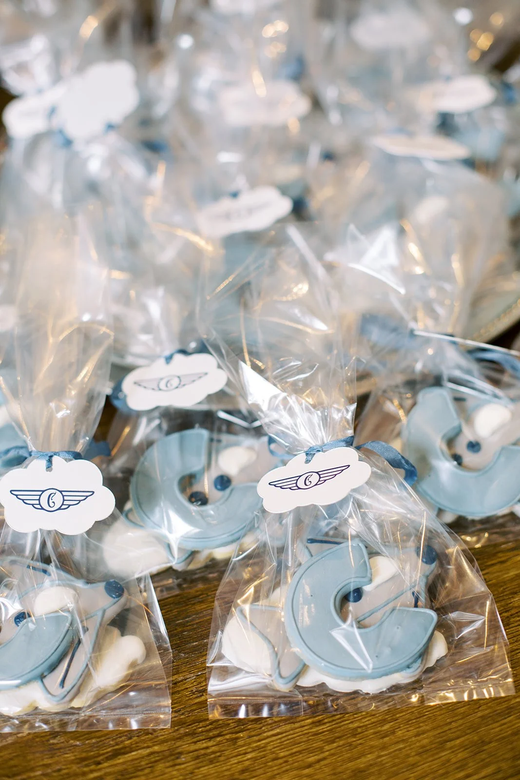 Coordinated day-of baby shower stationery including welcome signage, guest book check-in, baggage claim, paper airplane menus, and custom bar details inspired by the parents' love of flying and travel.