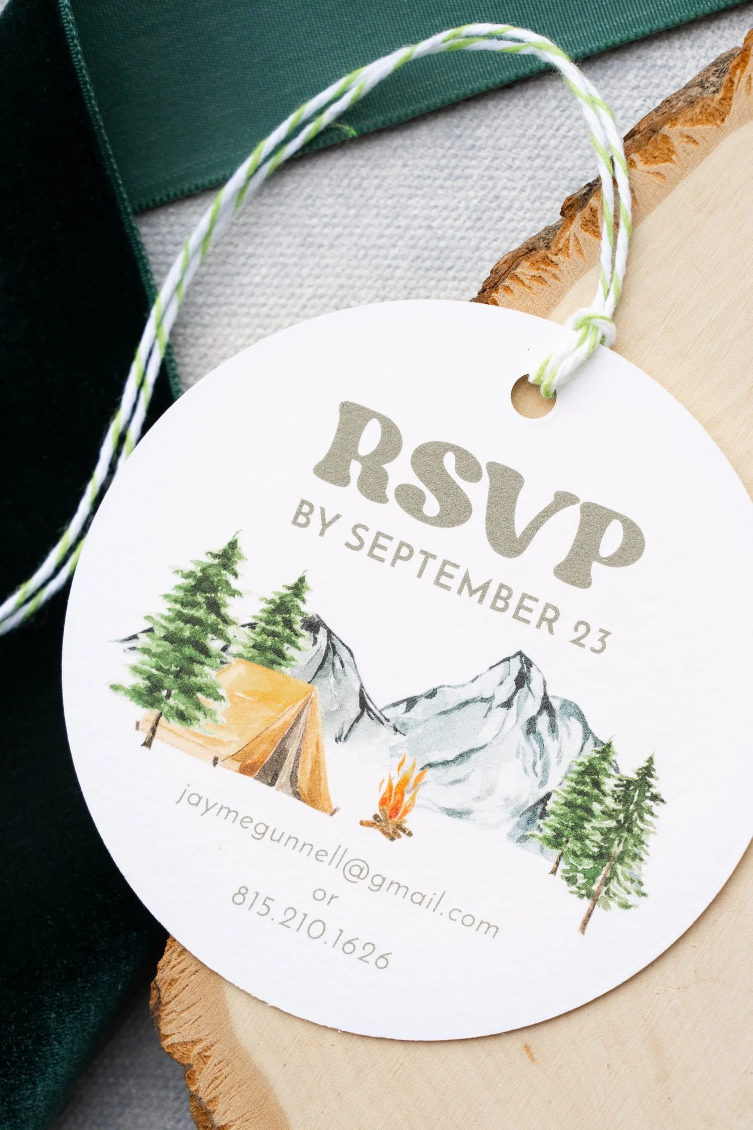 “One Happy Camper” first birthday invitation suite with plaid envelope liner, watercolor camping illustrations, die-cut campfire RSVP card, and green-and-white baker’s twine.